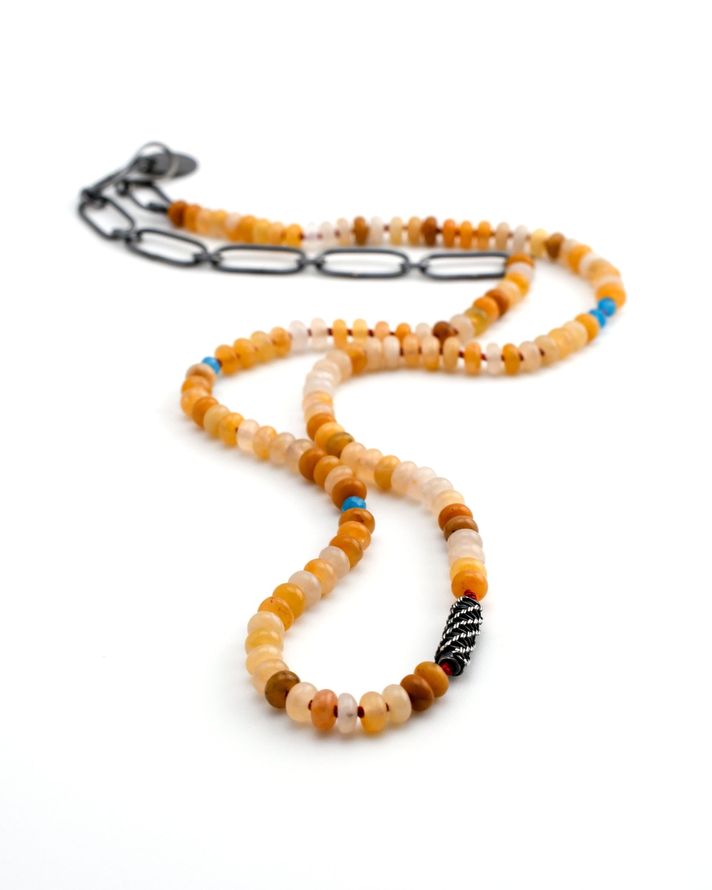 yellow jade beaded necklace with blue apatite accents and a silver woven bead and black silver chain on a white background