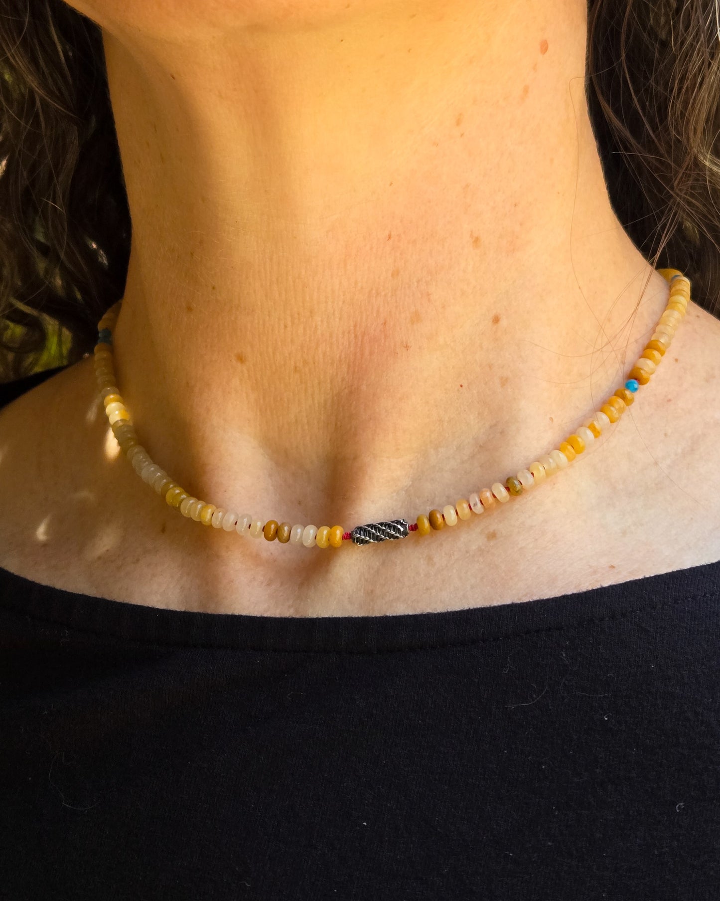 yellow jade beaded necklace with blue apatite and woven silver bead shown worn on a person, close to the throat