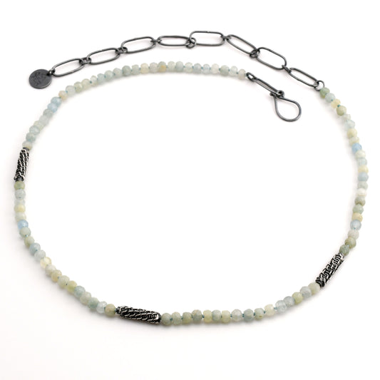 aquamarine beaded necklace with woven silver bead accents and black silver chain extender on a white background