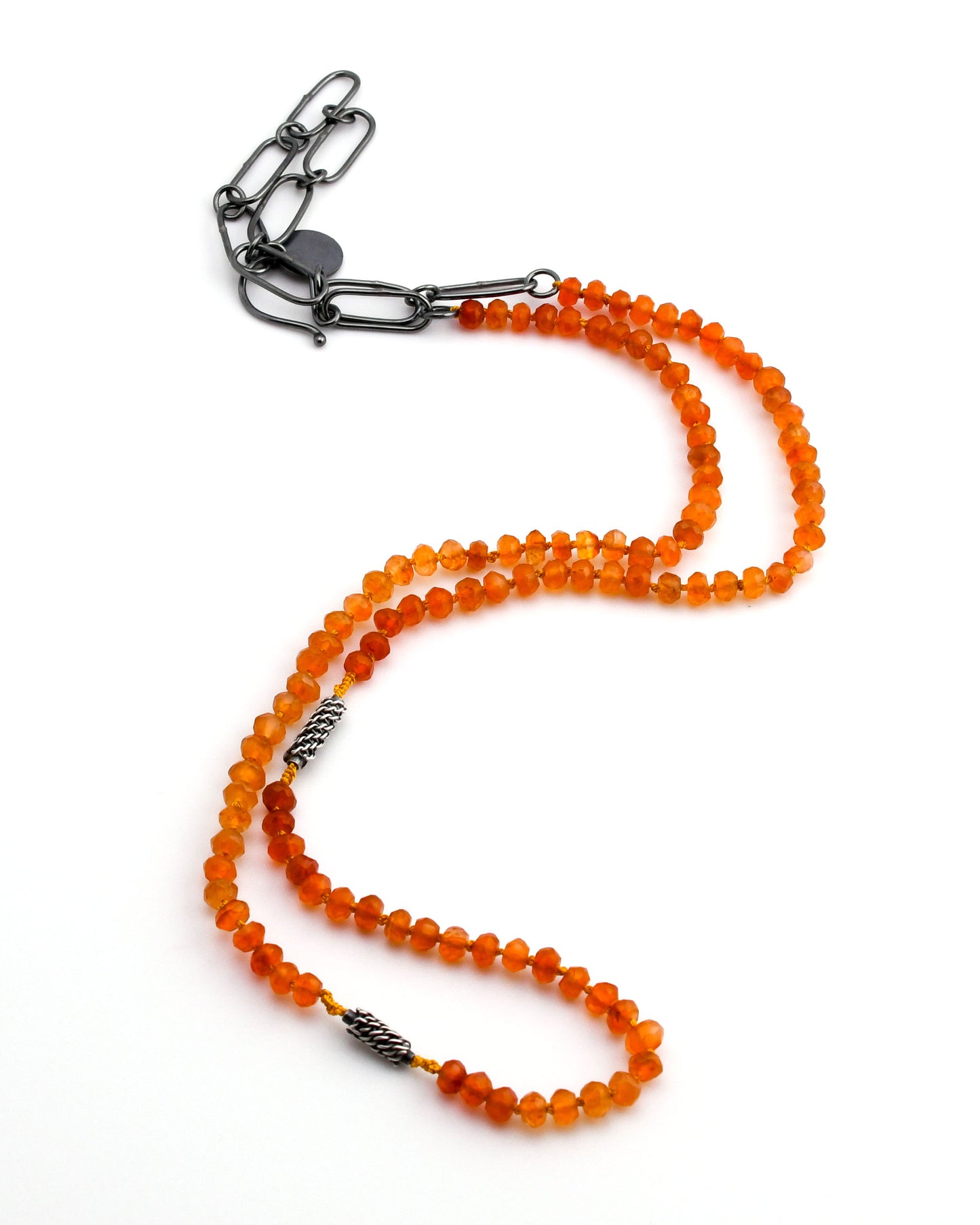 Orange carnelian beaded necklace with woven silver beads and black silver chain extender on a white background
