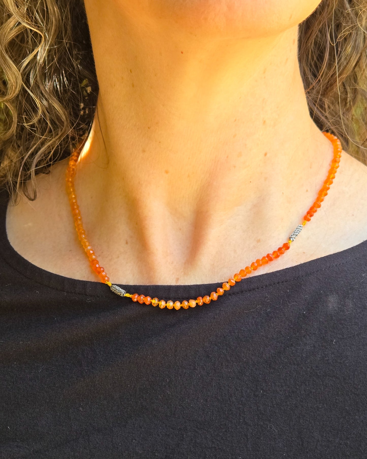 Orange carnelian beaded necklace worn close to the throat on a person  wearing a black shirt