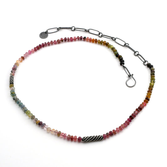 multi-color natural tourmaline beaded necklace with woven silver bead accents and black silver chain extender on a white background