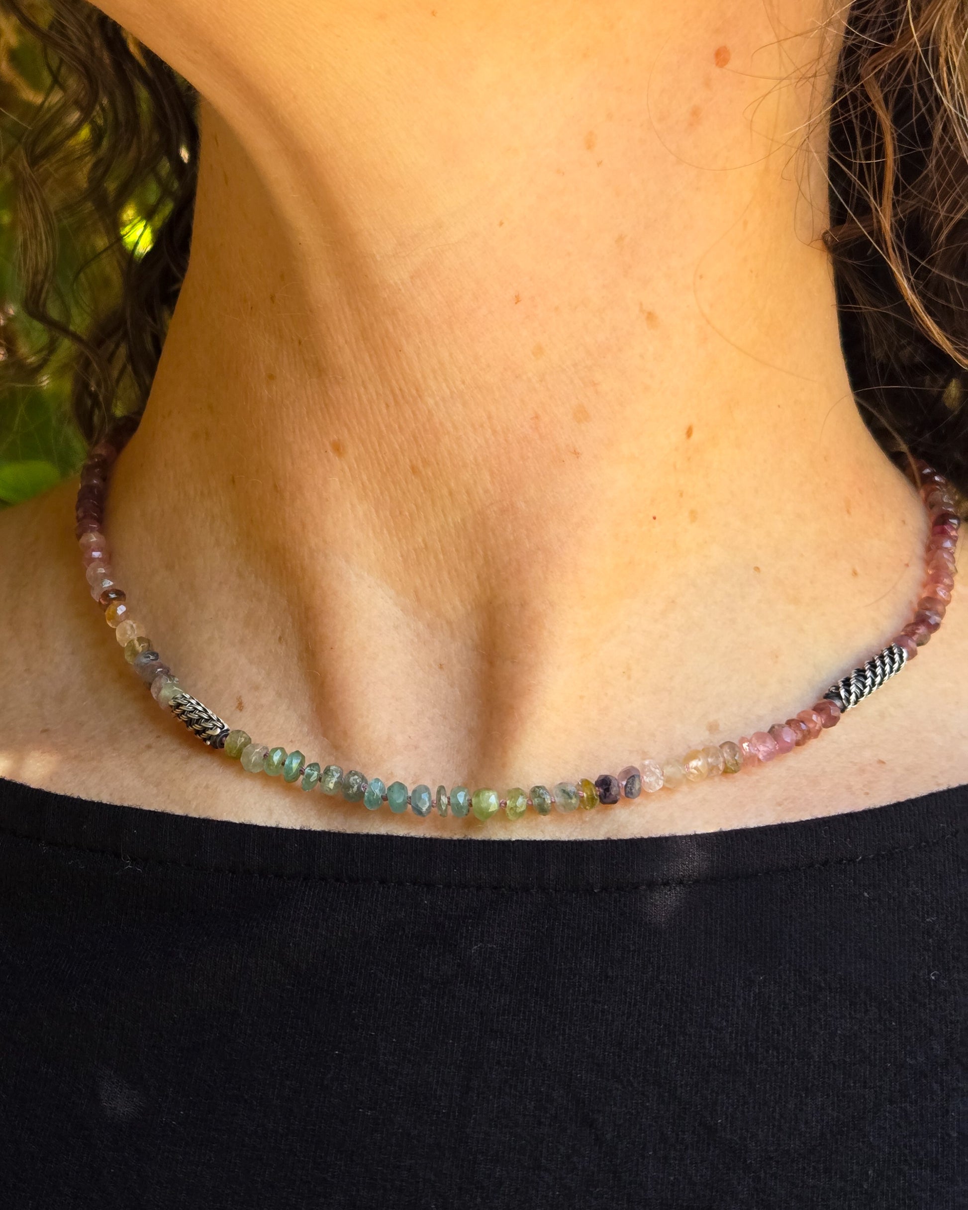 Close-up of a person wearing a multicolored beaded necklace close to the throat 
