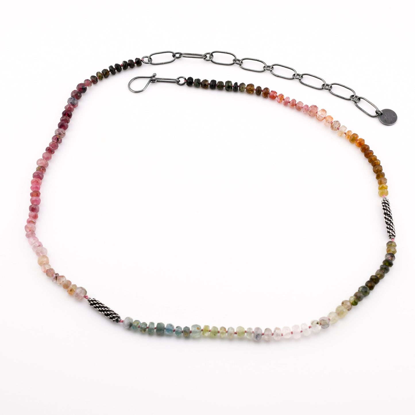 Necklace with multicolored beads and woven silver accents on a white background