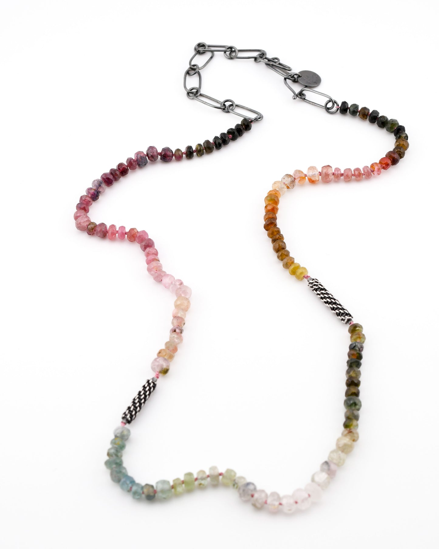 Necklace with multi-colored tourmaline beads and woven silver elements on a white background