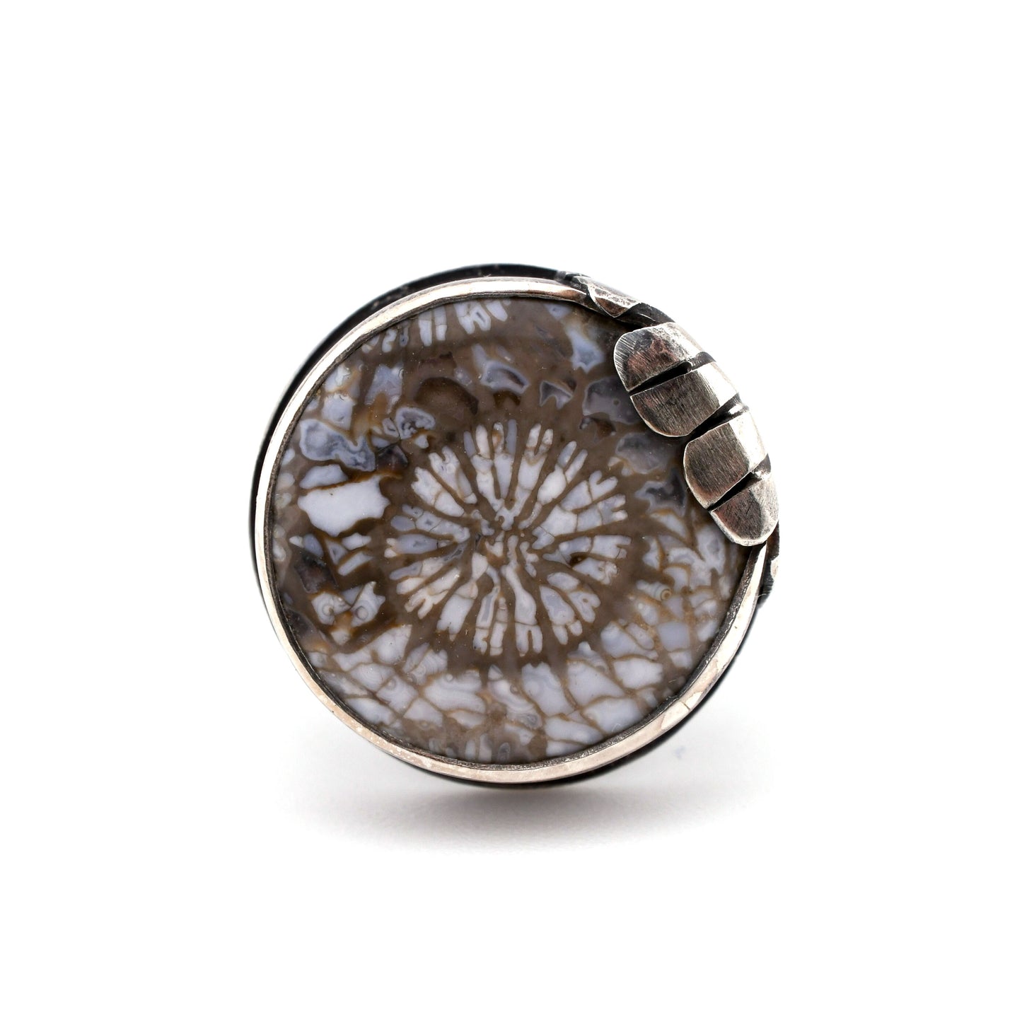 Round jewelry piece with a patterned design on a white background