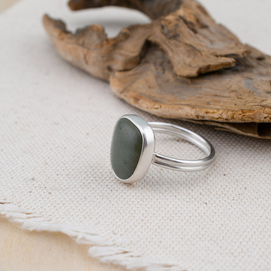 Silver ring with a gray-blue stone on a textured fabric background