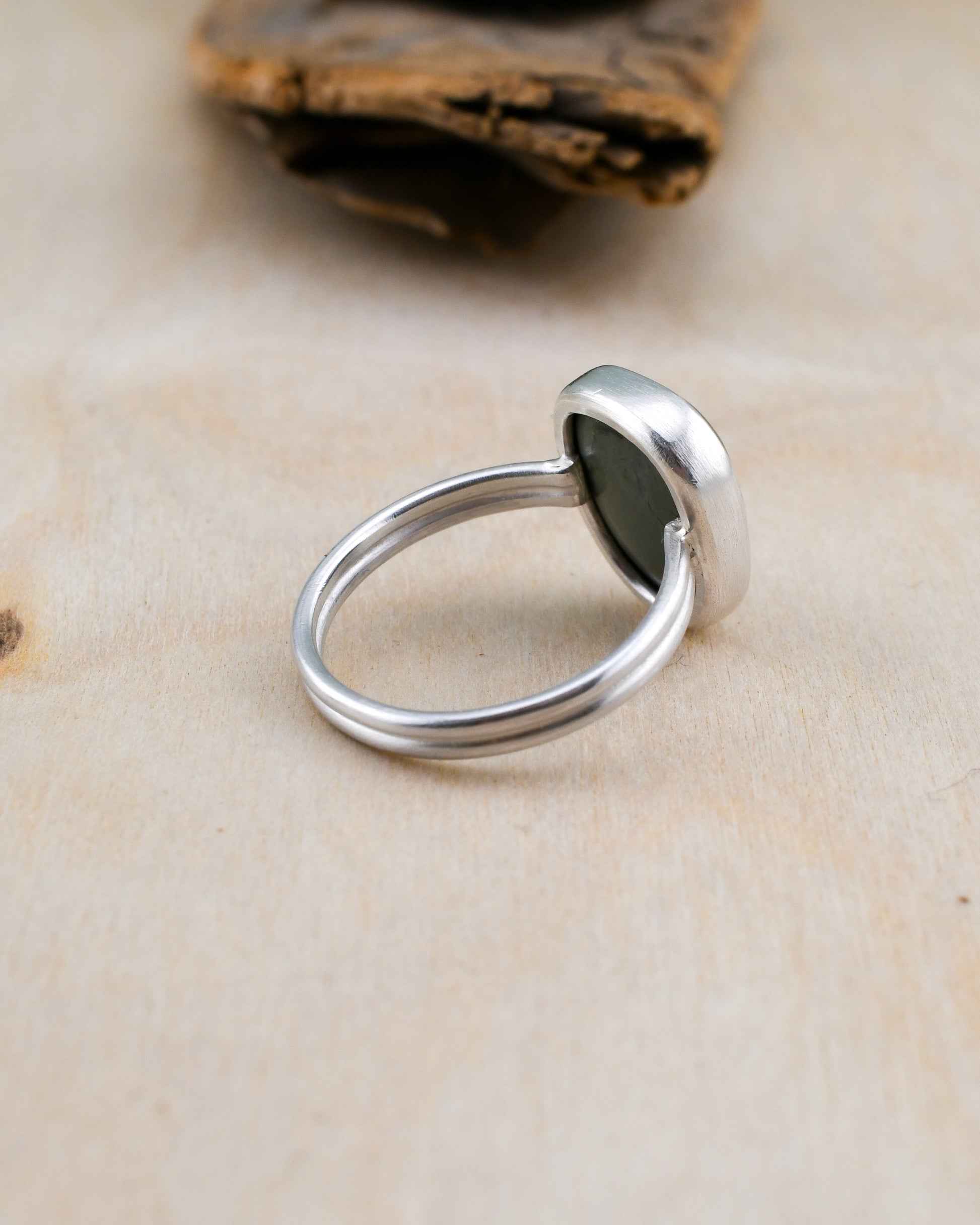 Backside of silver ring with gray-blue stone on a wooden background