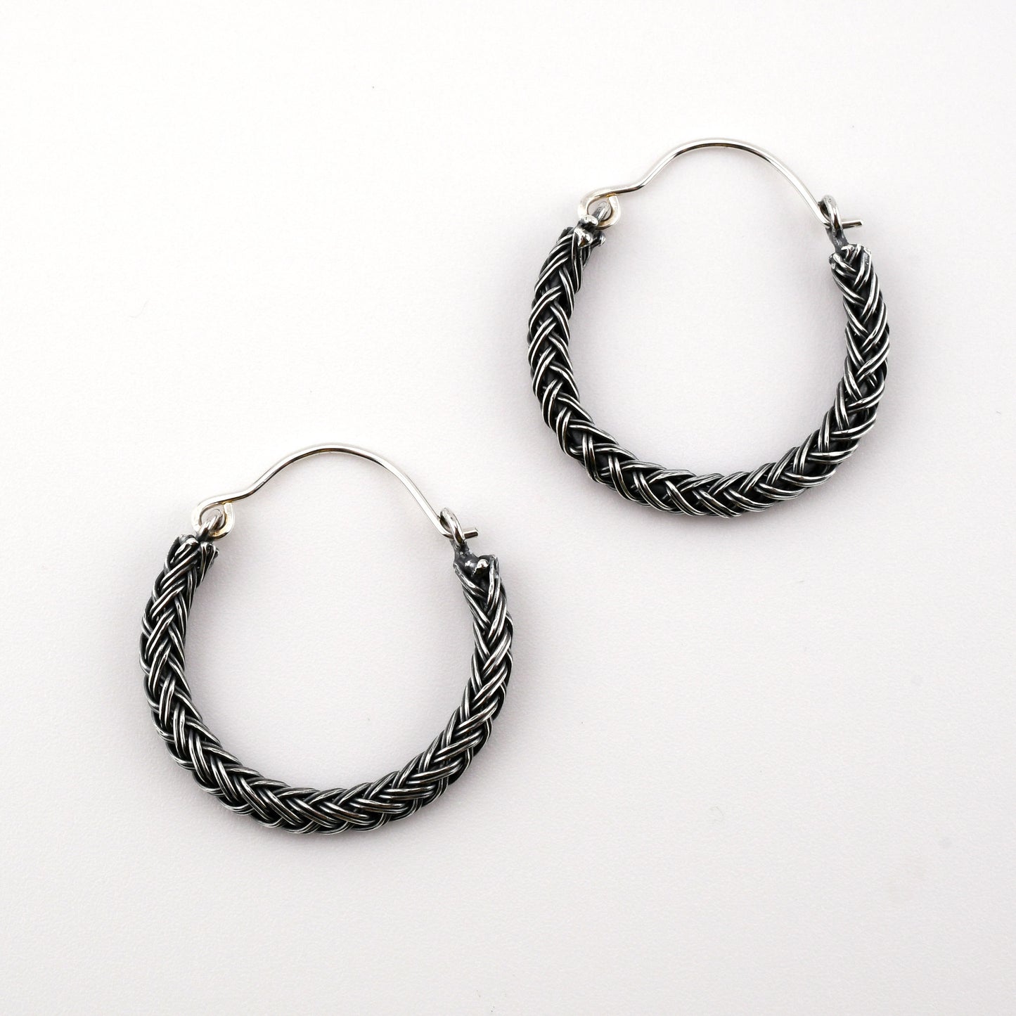 Pair of braided hoop earrings on a white background