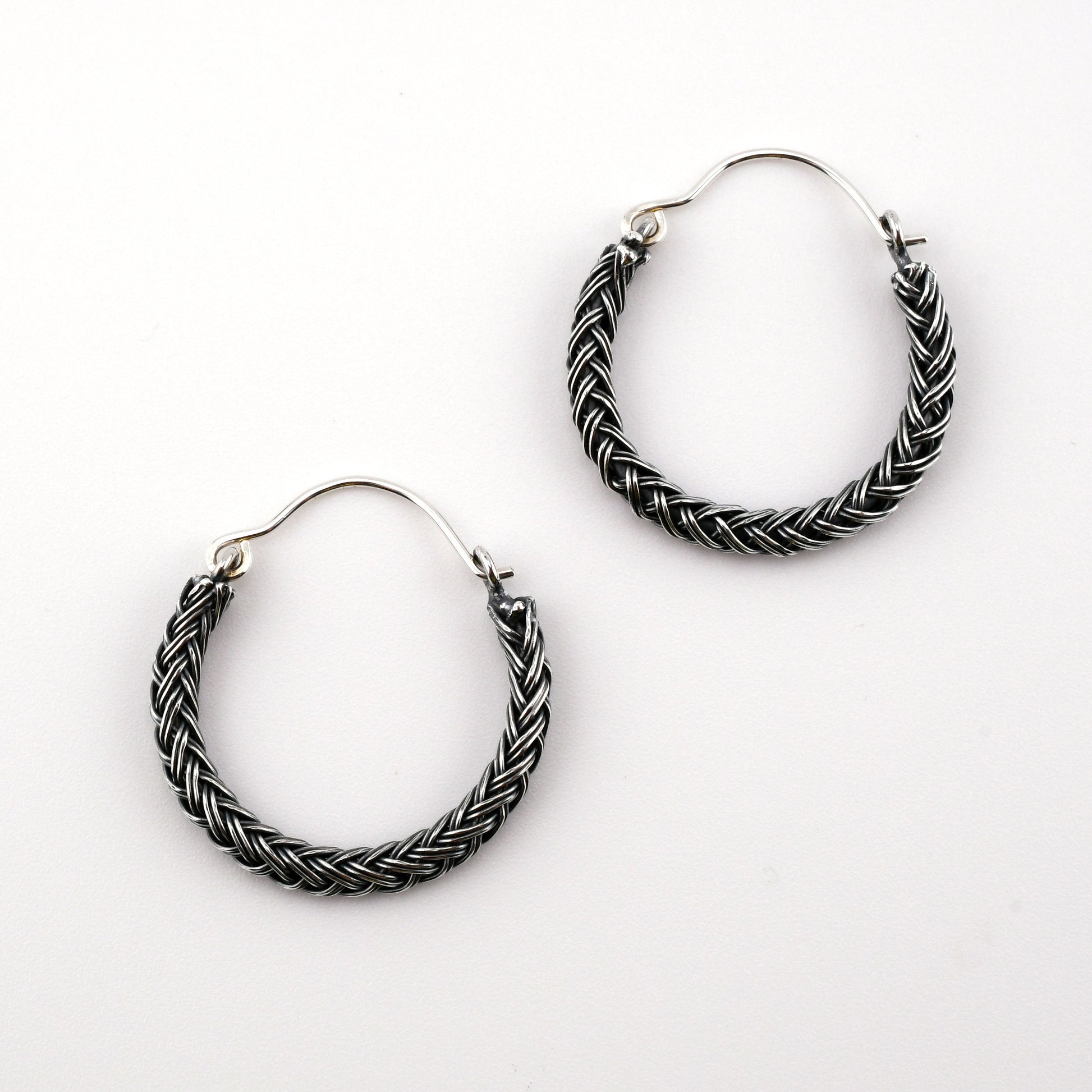 Pair of braided hoop earrings on a white background