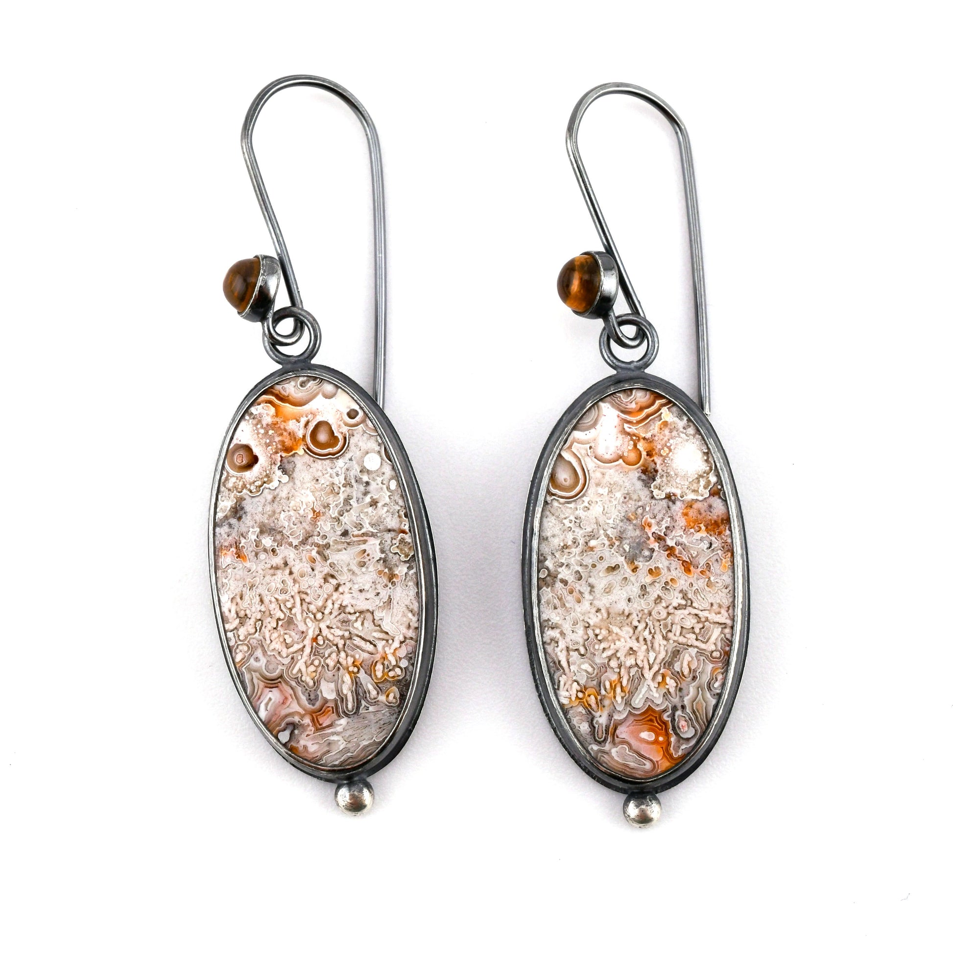 Pair of earrings with oval stones on a white background