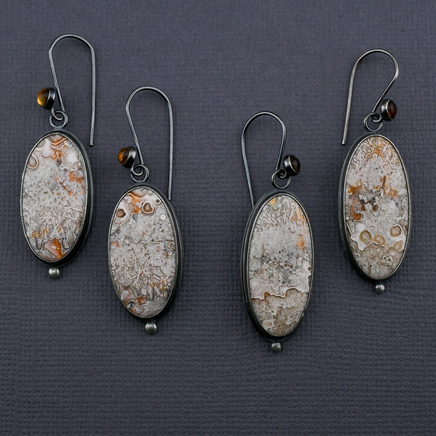 Two pairs of earrings with crazy lace agate and citrines on a dark gray background