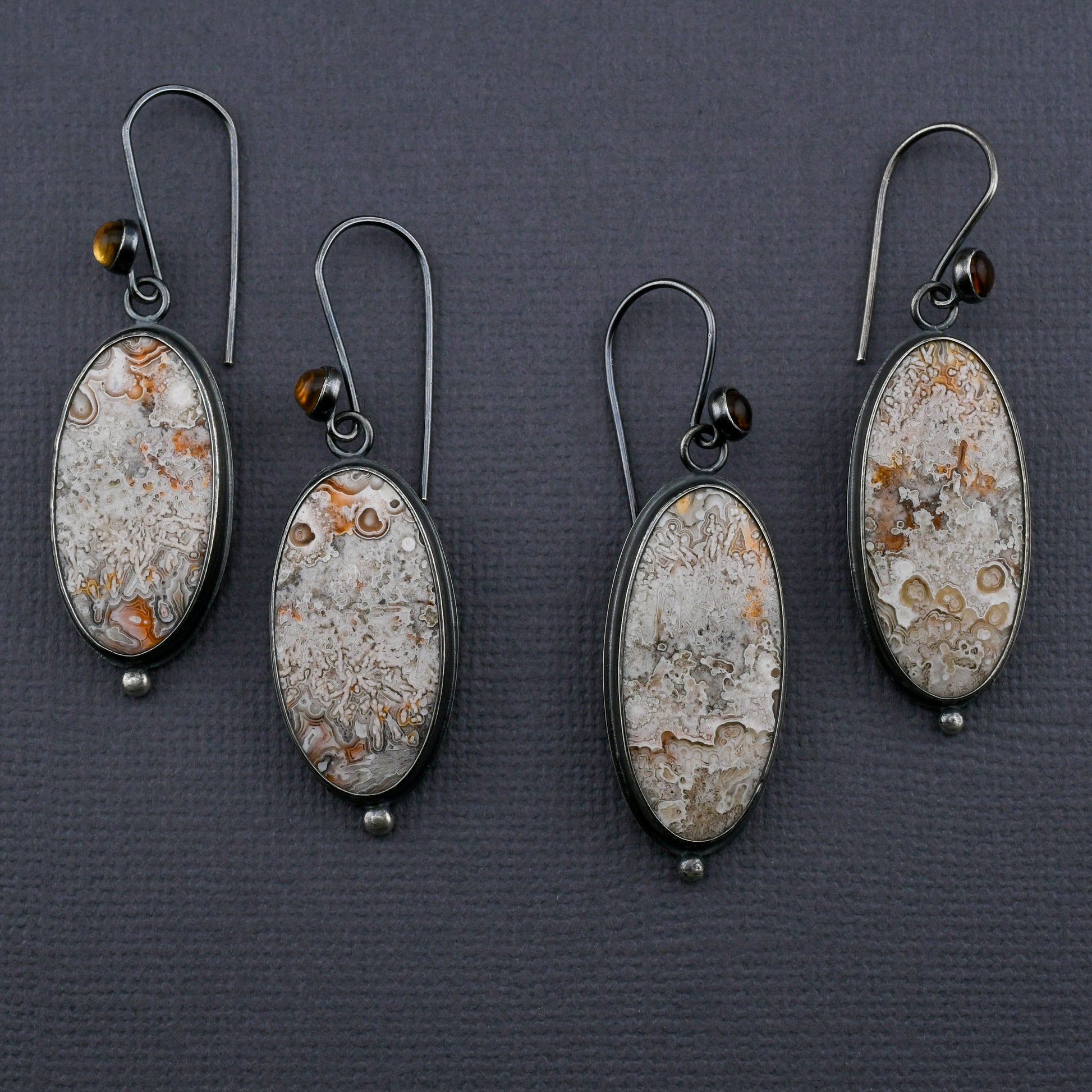 Two pairs of earrings with crazy lace agate and citrines on a dark gray background