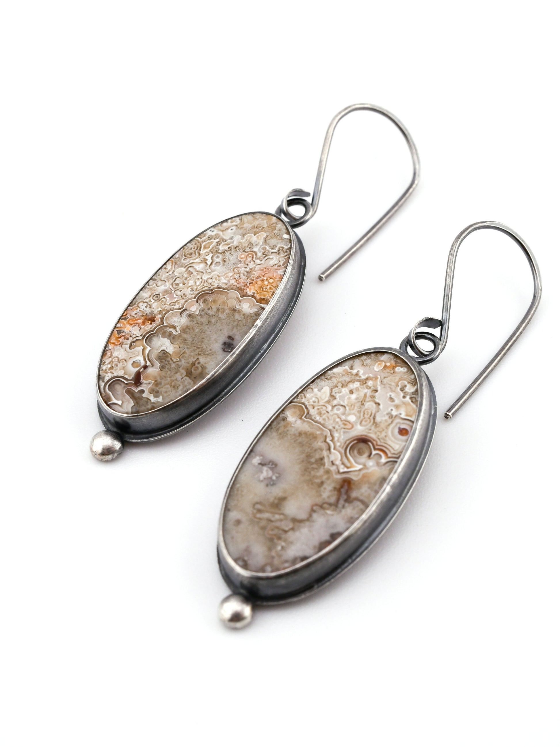 Pair of silver earrings with natural stones on a white background