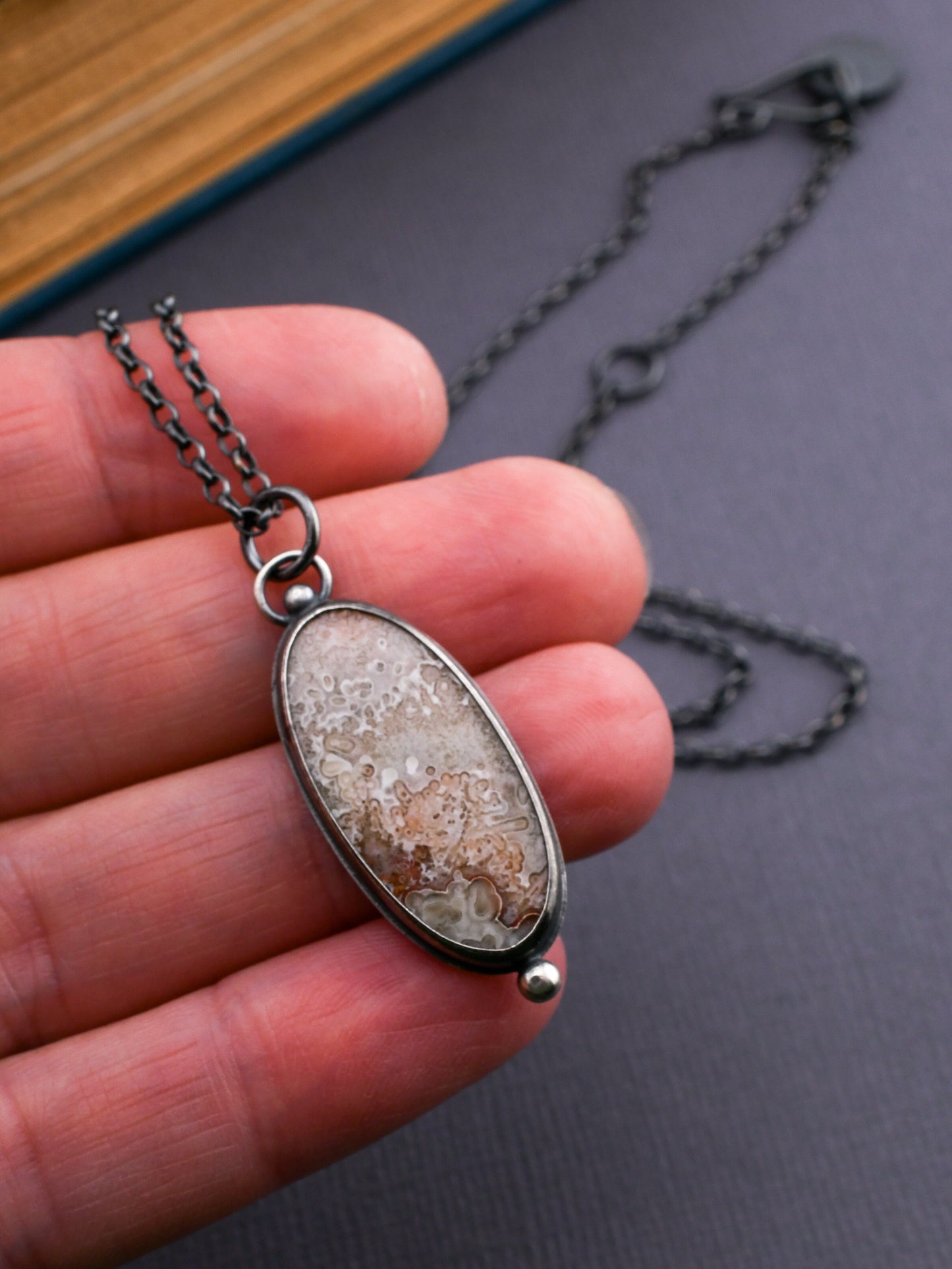 Necklace with a pendant held in a hand against a dark background