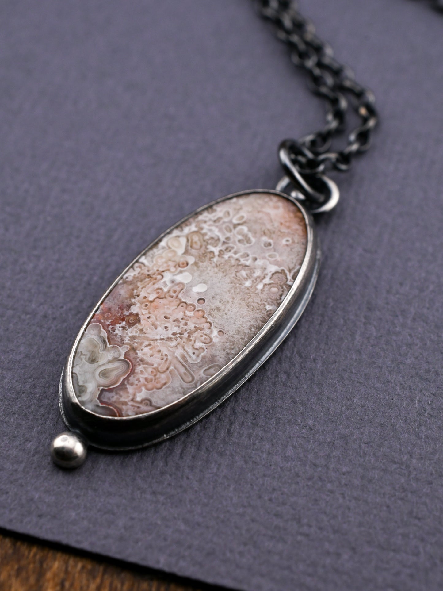 Necklace with an oval pendant on a textured gray surface