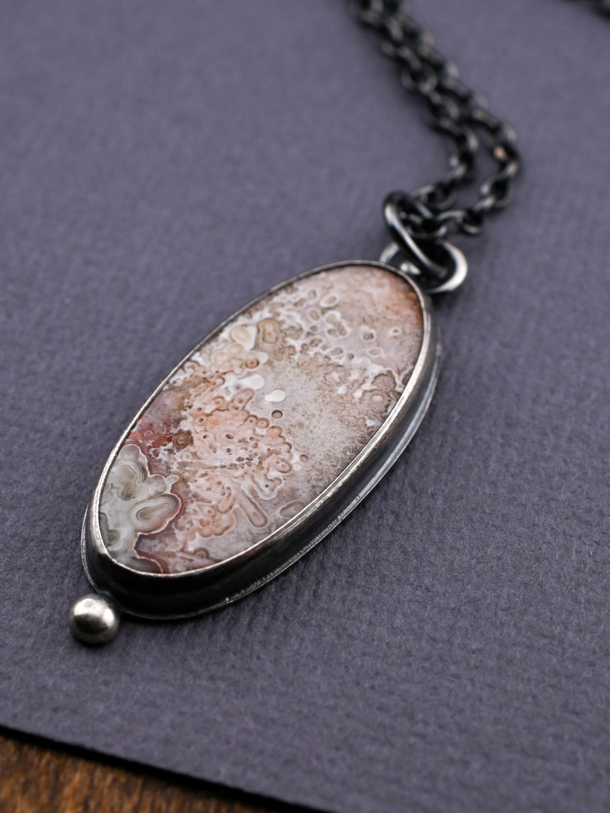 Necklace with an oval pendant on a textured gray surface