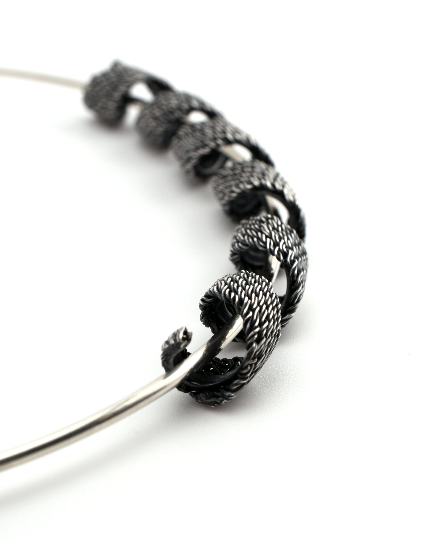 closeup of woven silver form coiled around a silver torque neck-form