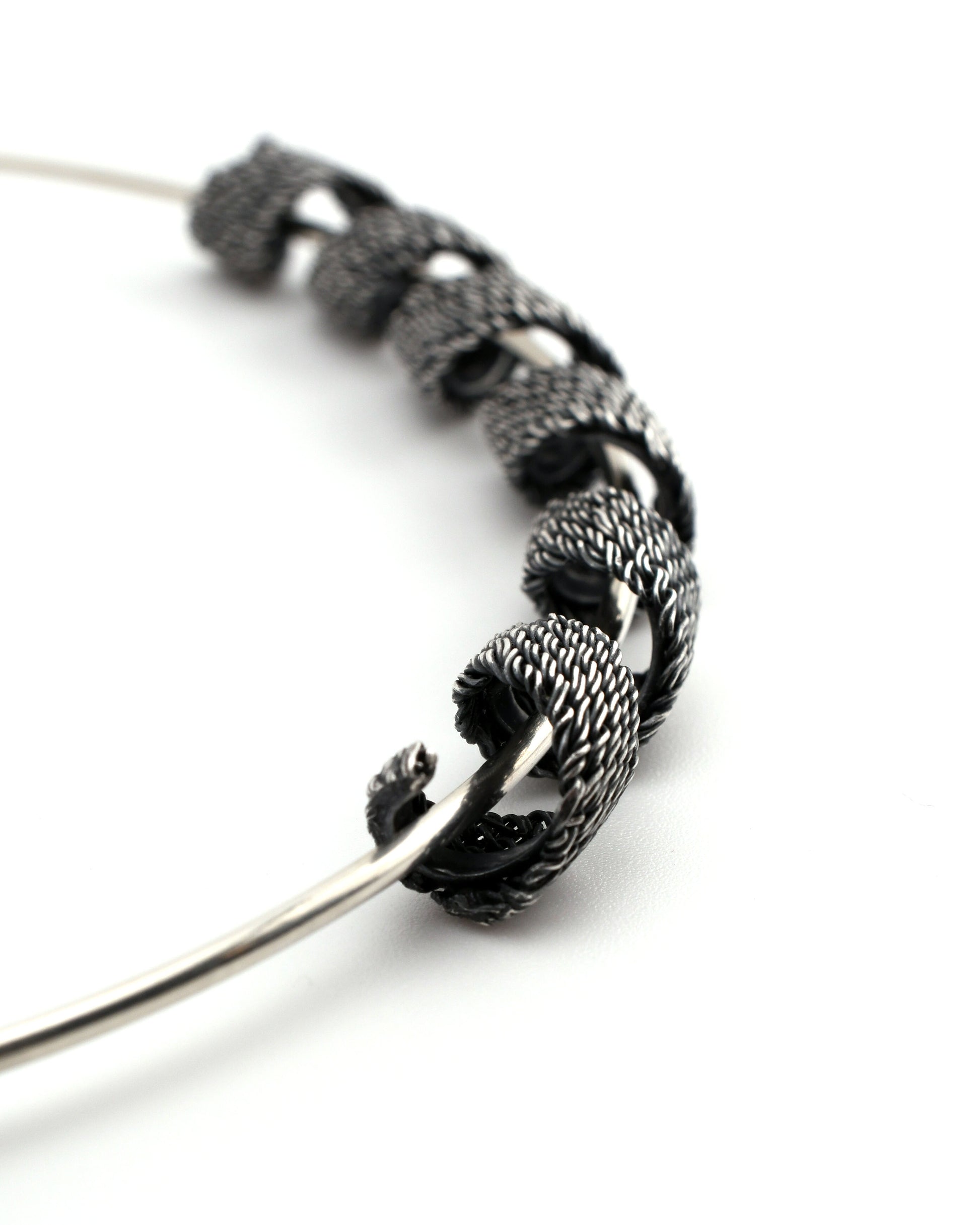 closeup of woven silver form coiled around a silver torque neck-form