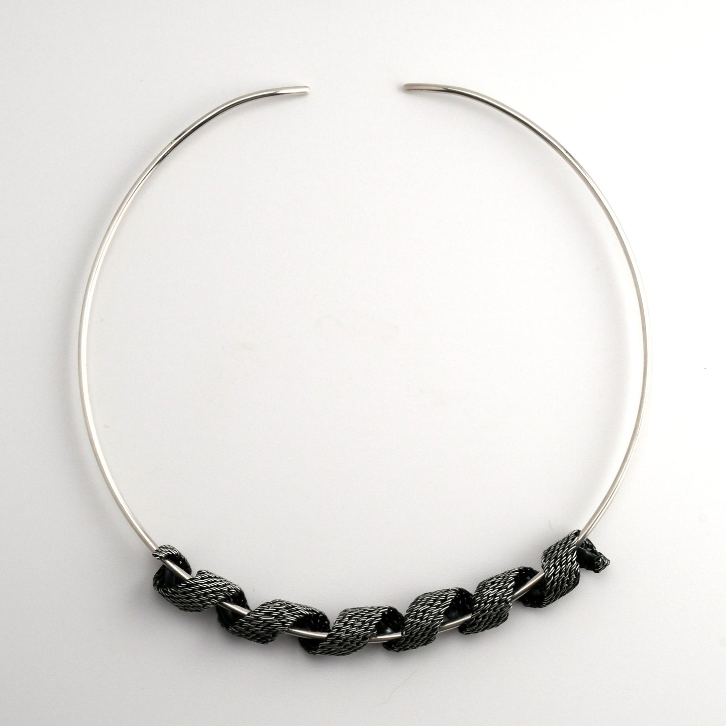 Silver torque necklace with woven silver form coiled around the neckpiece on a white background