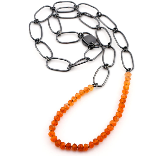 Necklace with black chain and orange beads on a white background