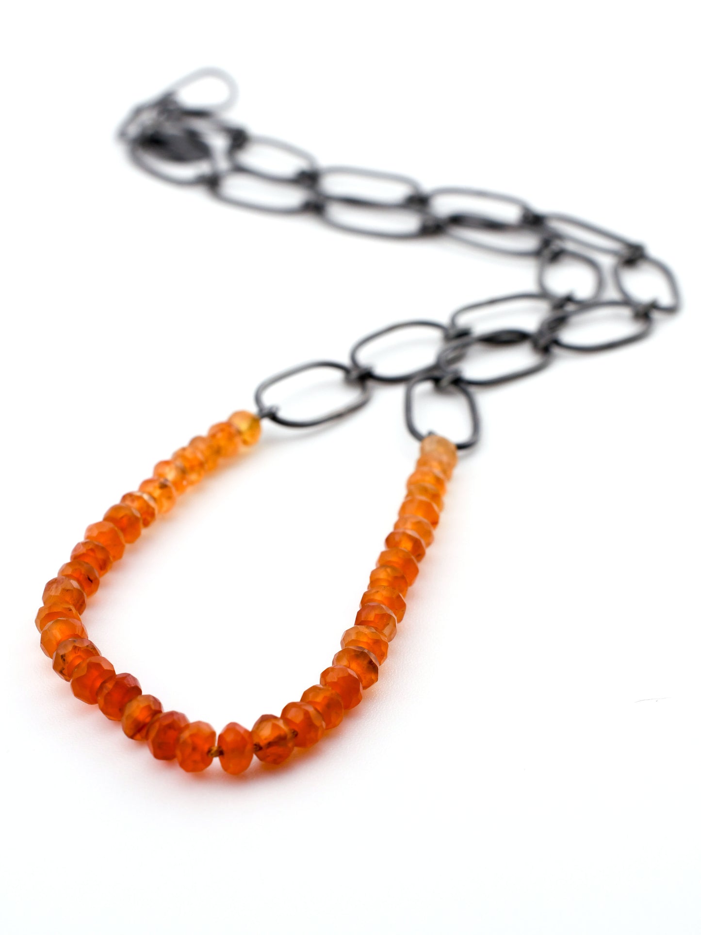 Necklace with orange beads and black chain on a white background