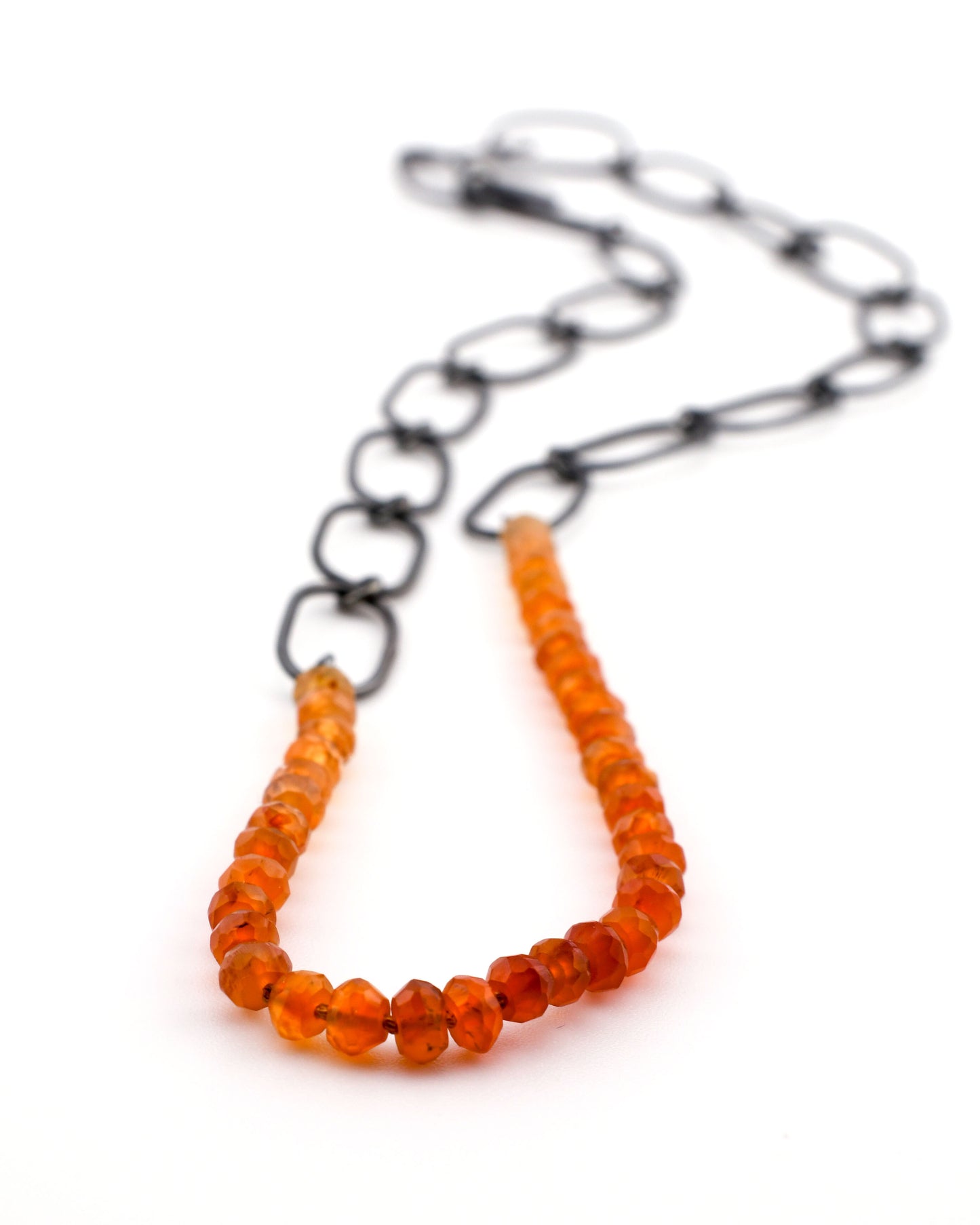 Necklace with orange beads and a black chain on a white background