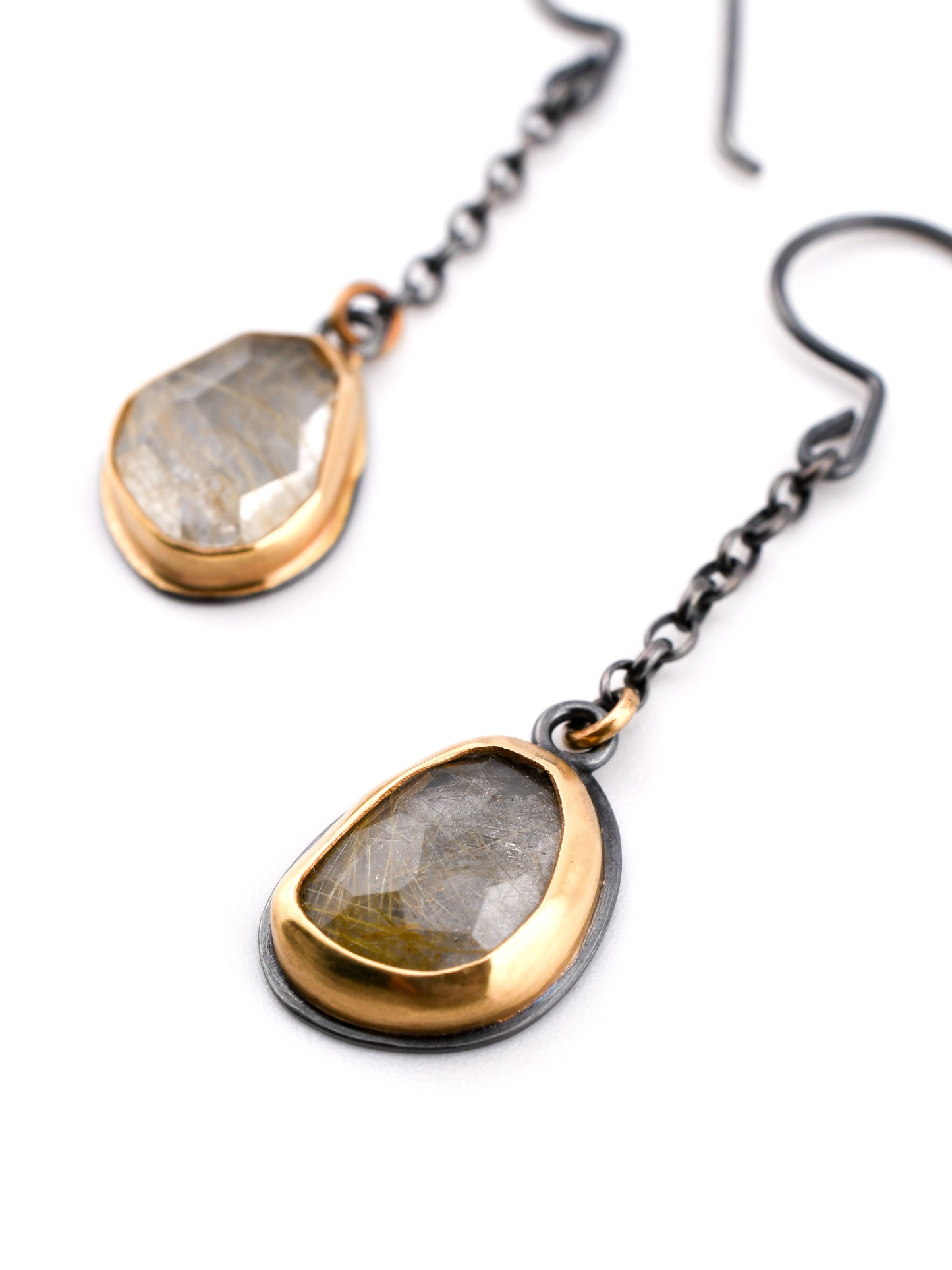 Black and gold earrings with chain details and rutilated quartz on a white background
