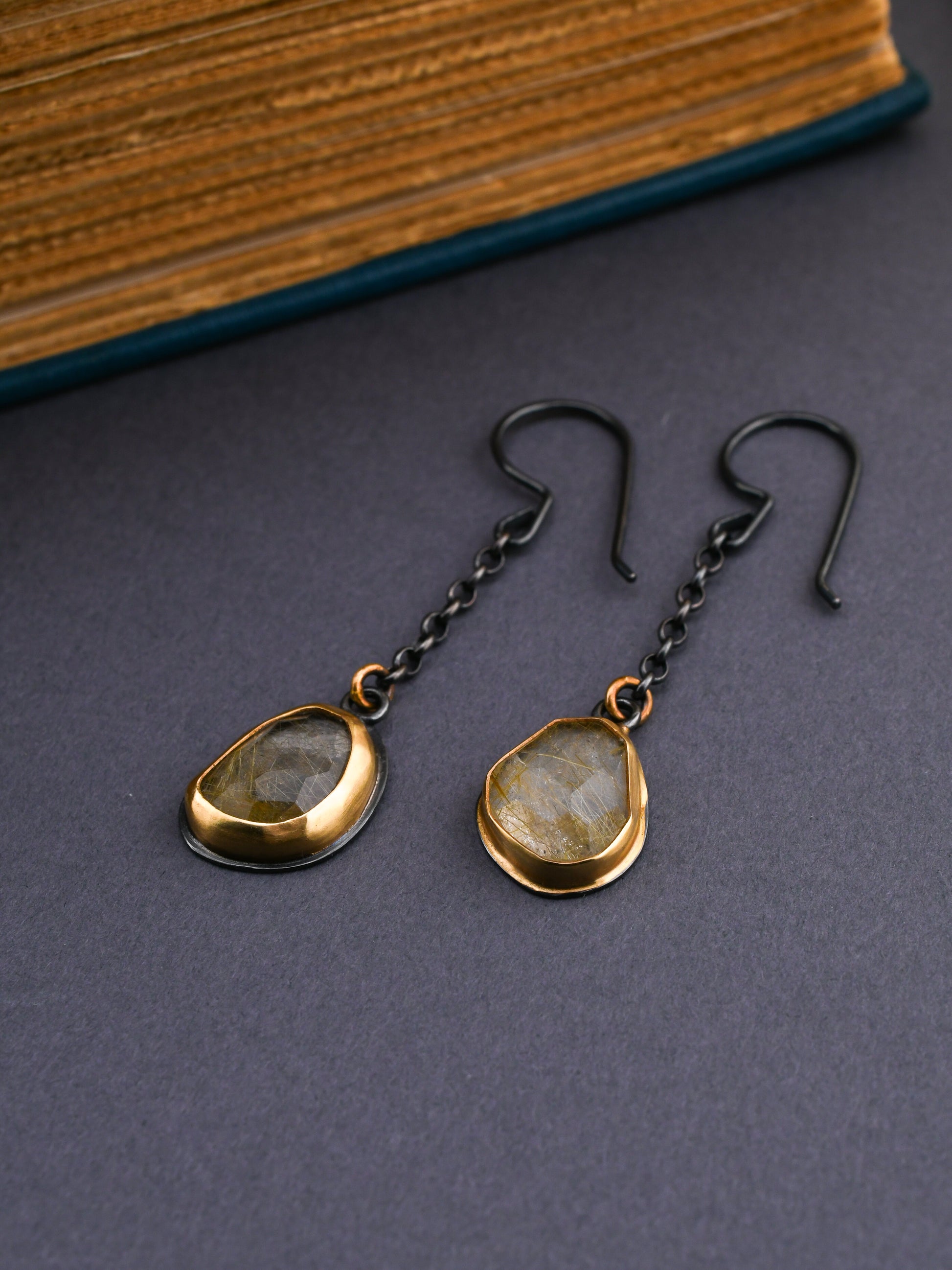 Pair of earrings with teardrop-shaped stones on a dark surface
