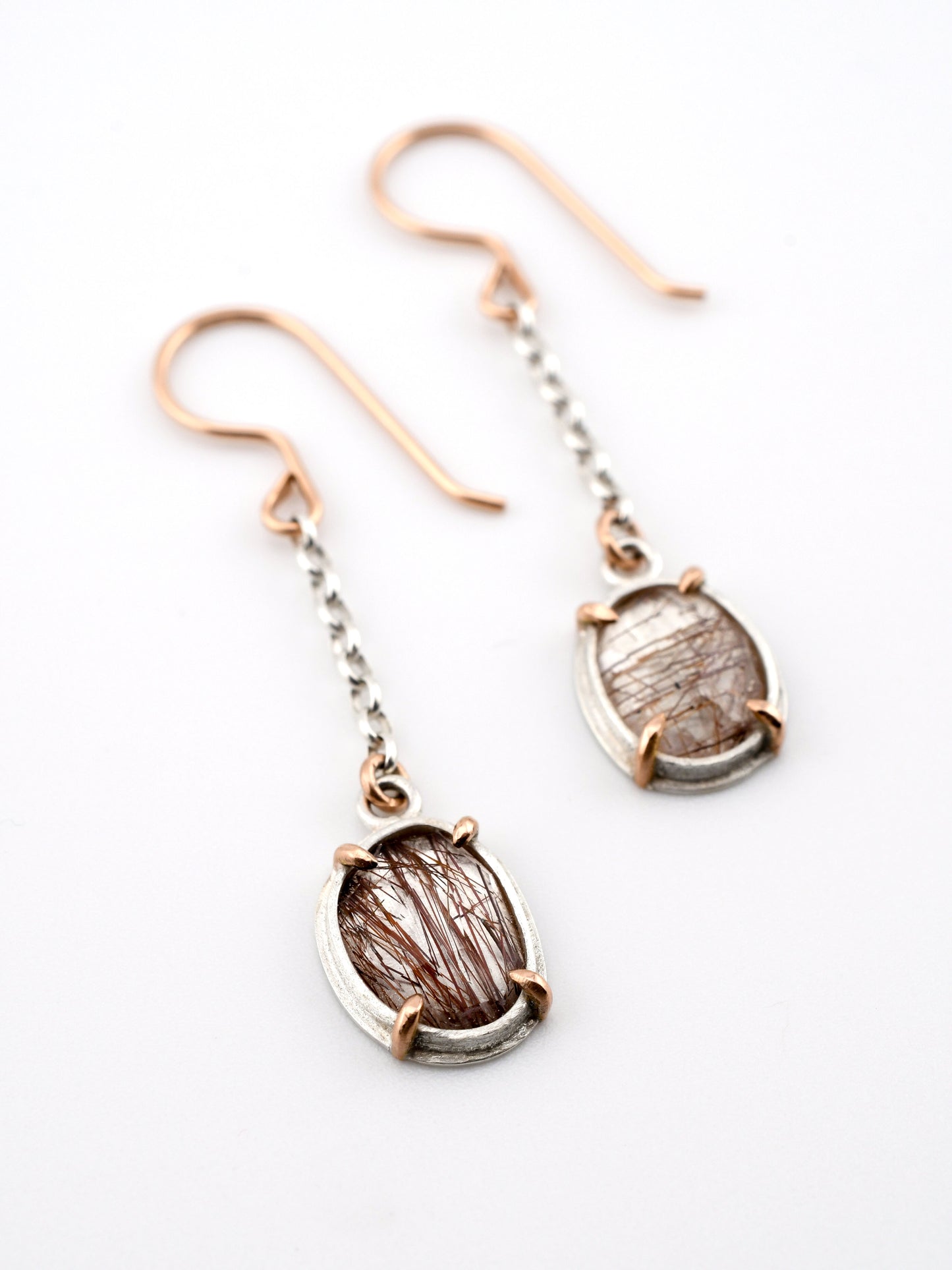 Pair of earrings with rose gold and silver hooks on a white background