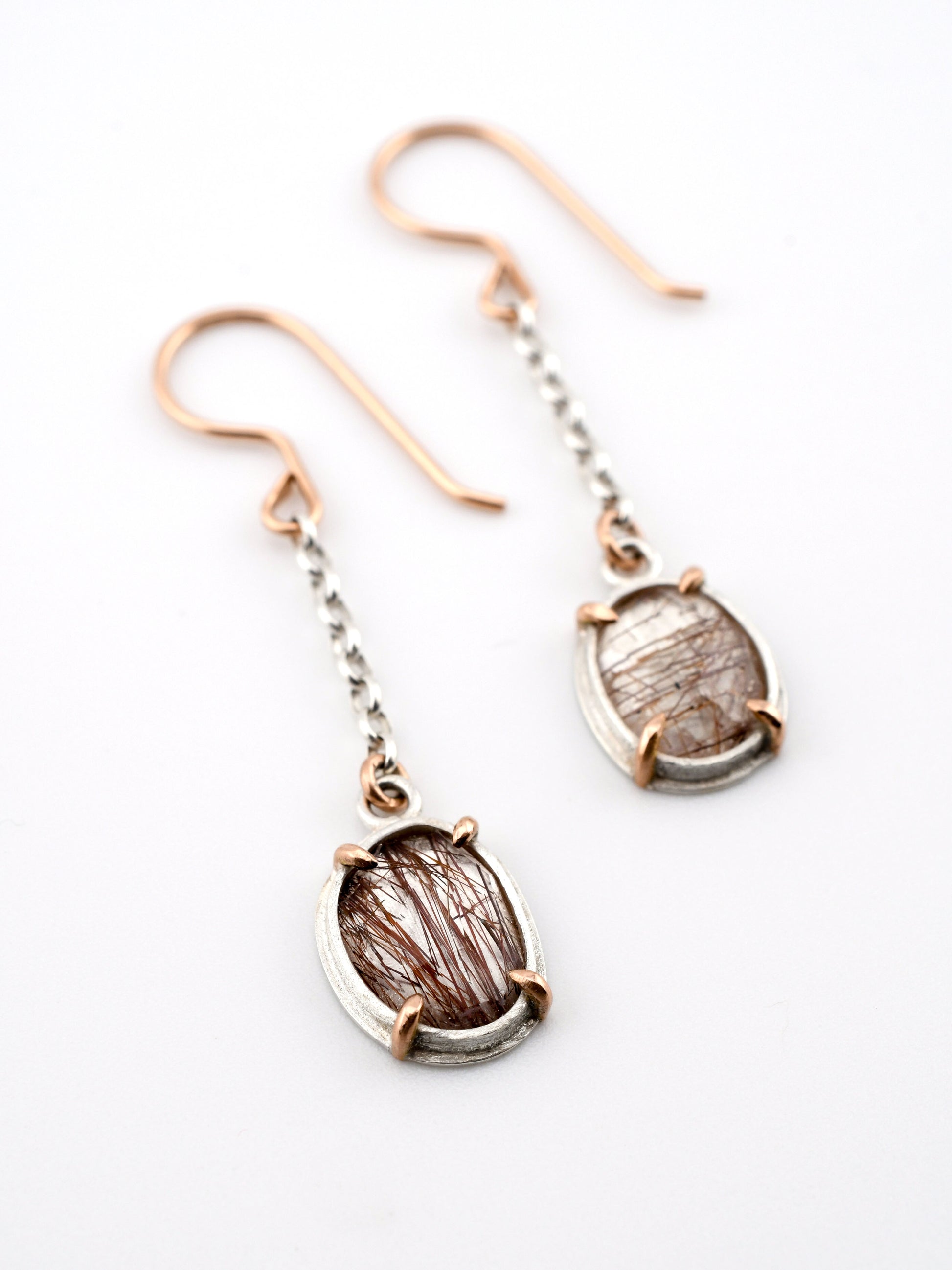Pair of earrings with rose gold and silver hooks on a white background