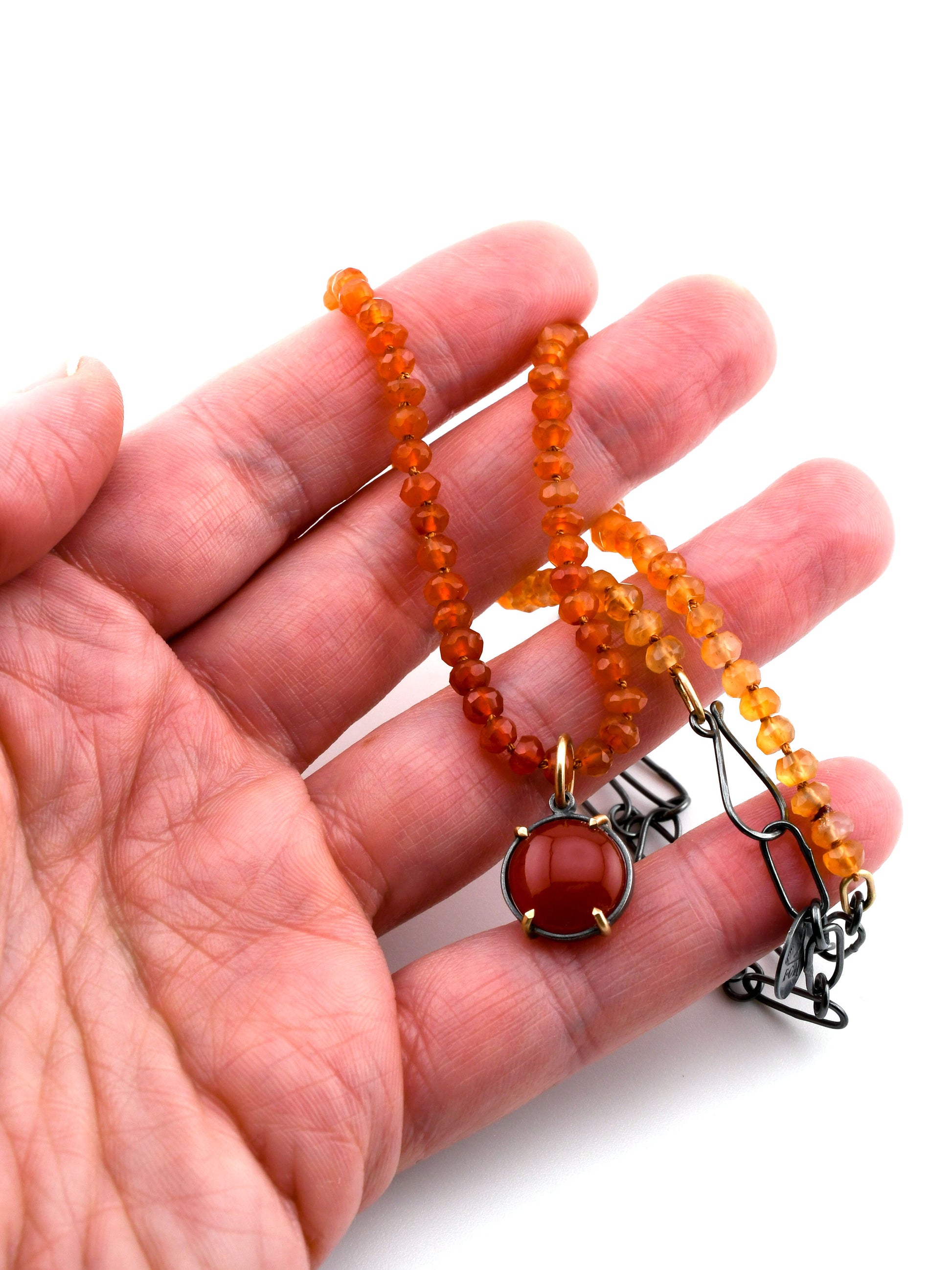 Hand holding a beaded necklaces with a white background