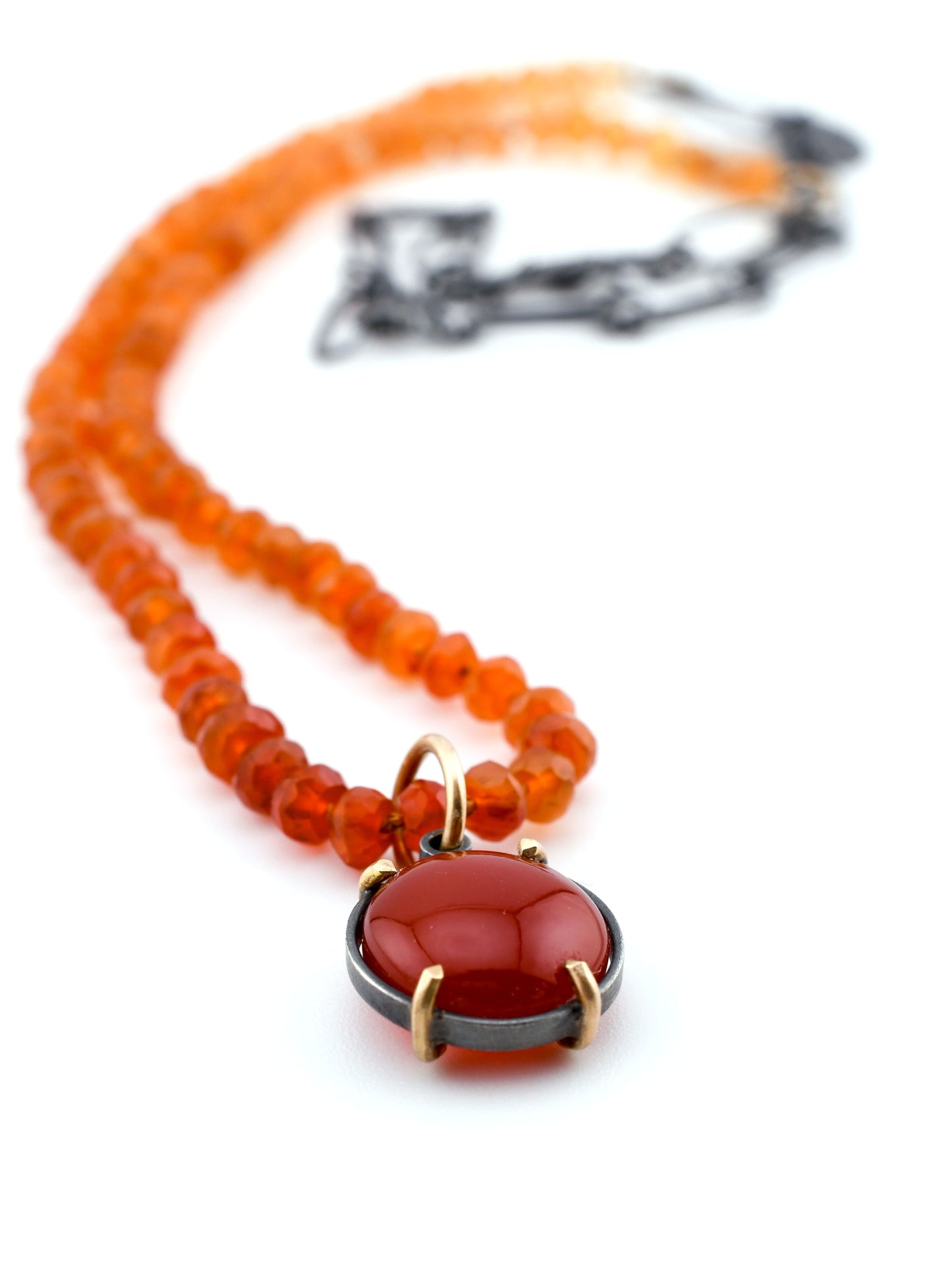 Necklace with orange beads and a red pendant on a white background