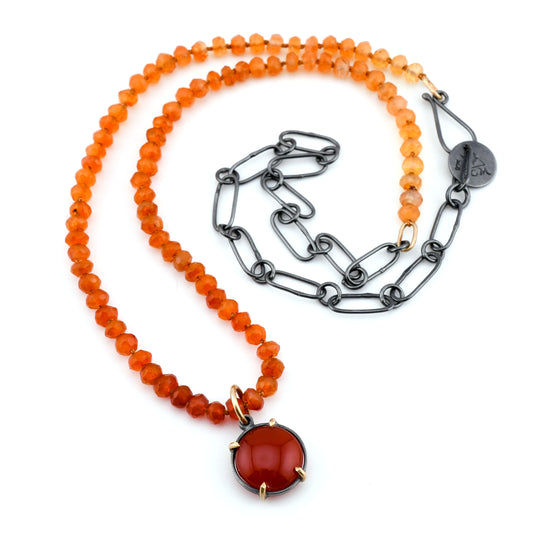 Necklace with orange beads and a red pendant on a white background