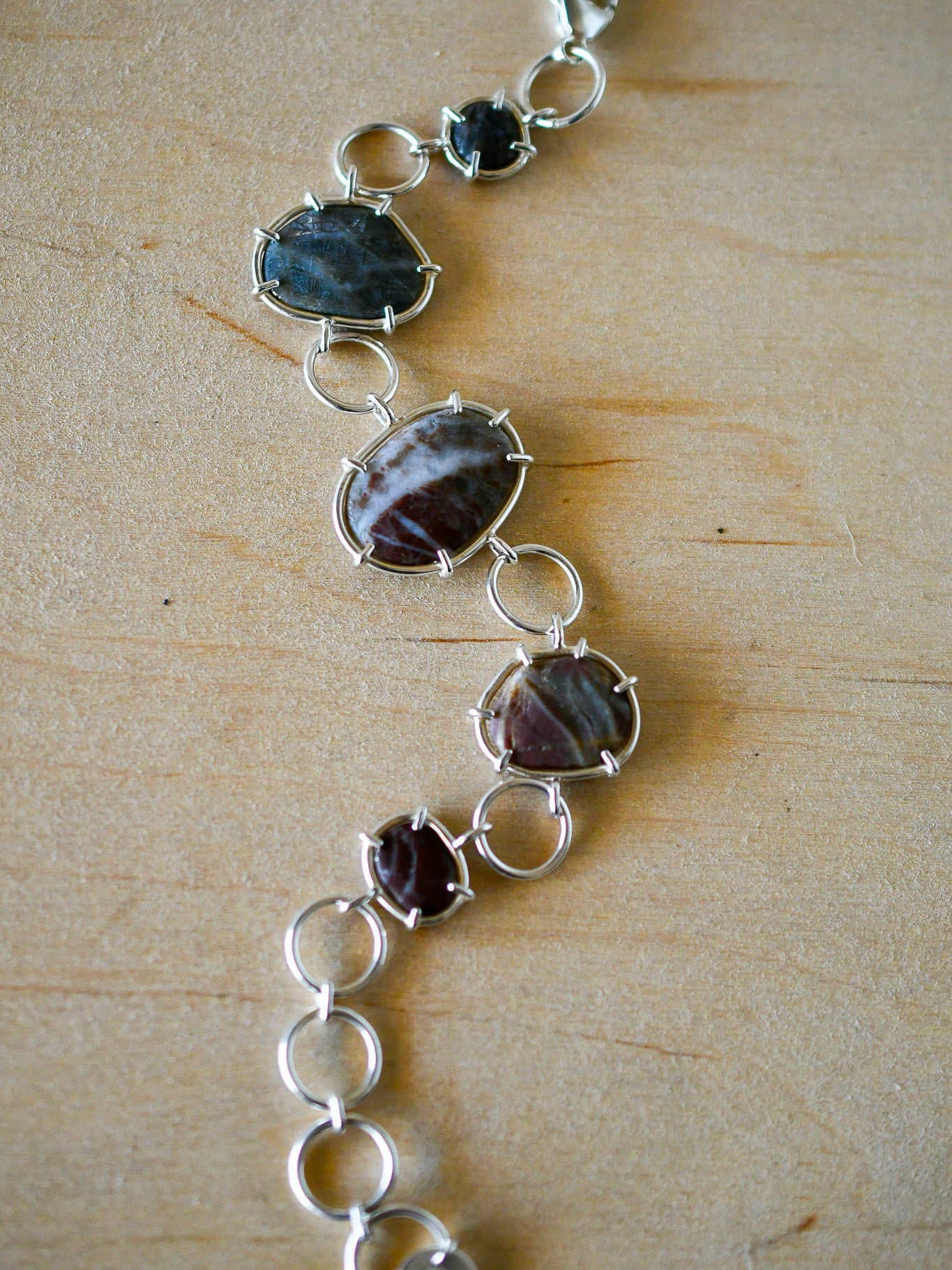 Silver bracelet with green and red textured beach stoned on a neutral background
