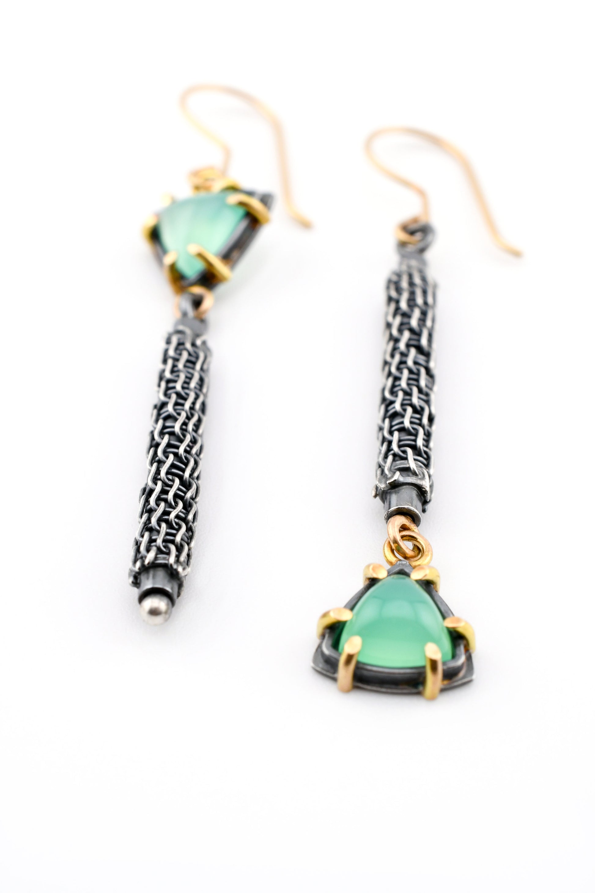 Pair of earrings with green gemstones and woven designs on a white background