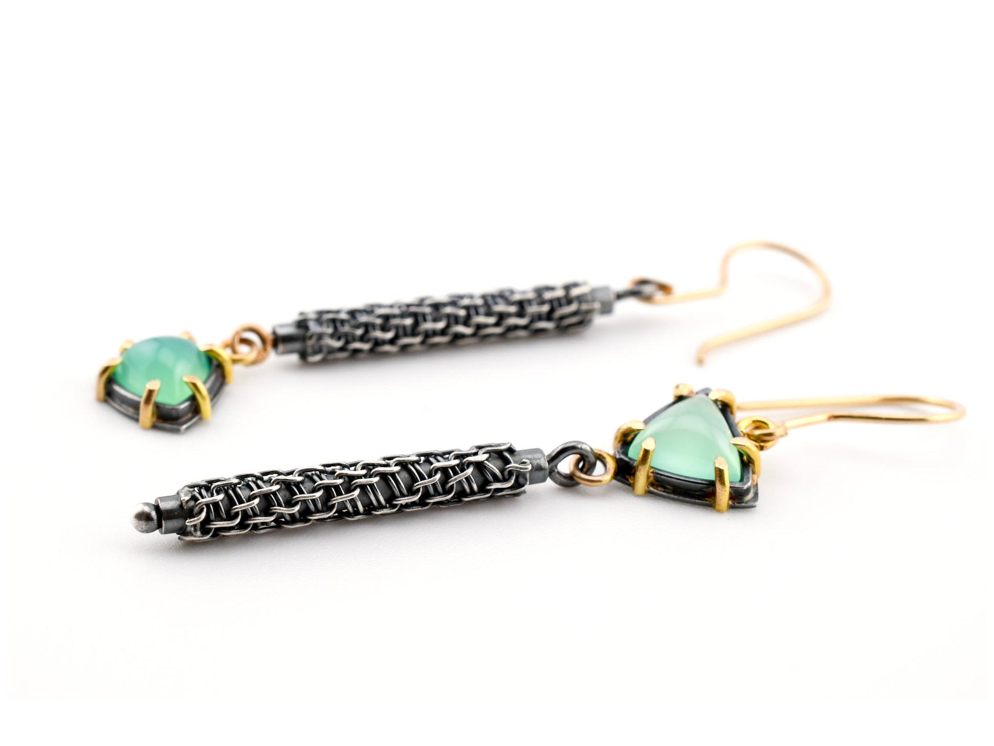 Pair of earrings with green gemstones and silver weaving on a white background