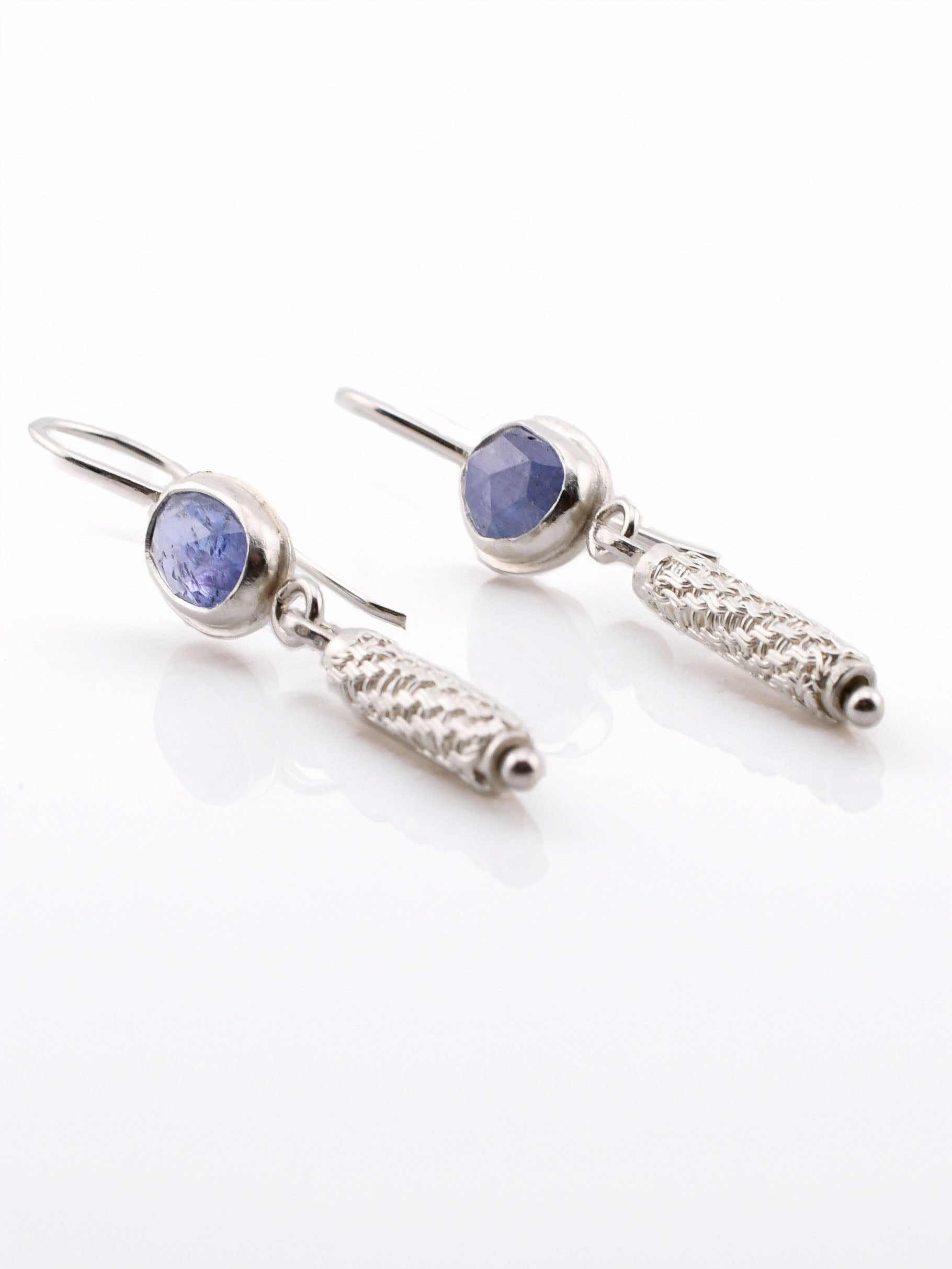 Pair of silver earrings with blue gemstones on a white background