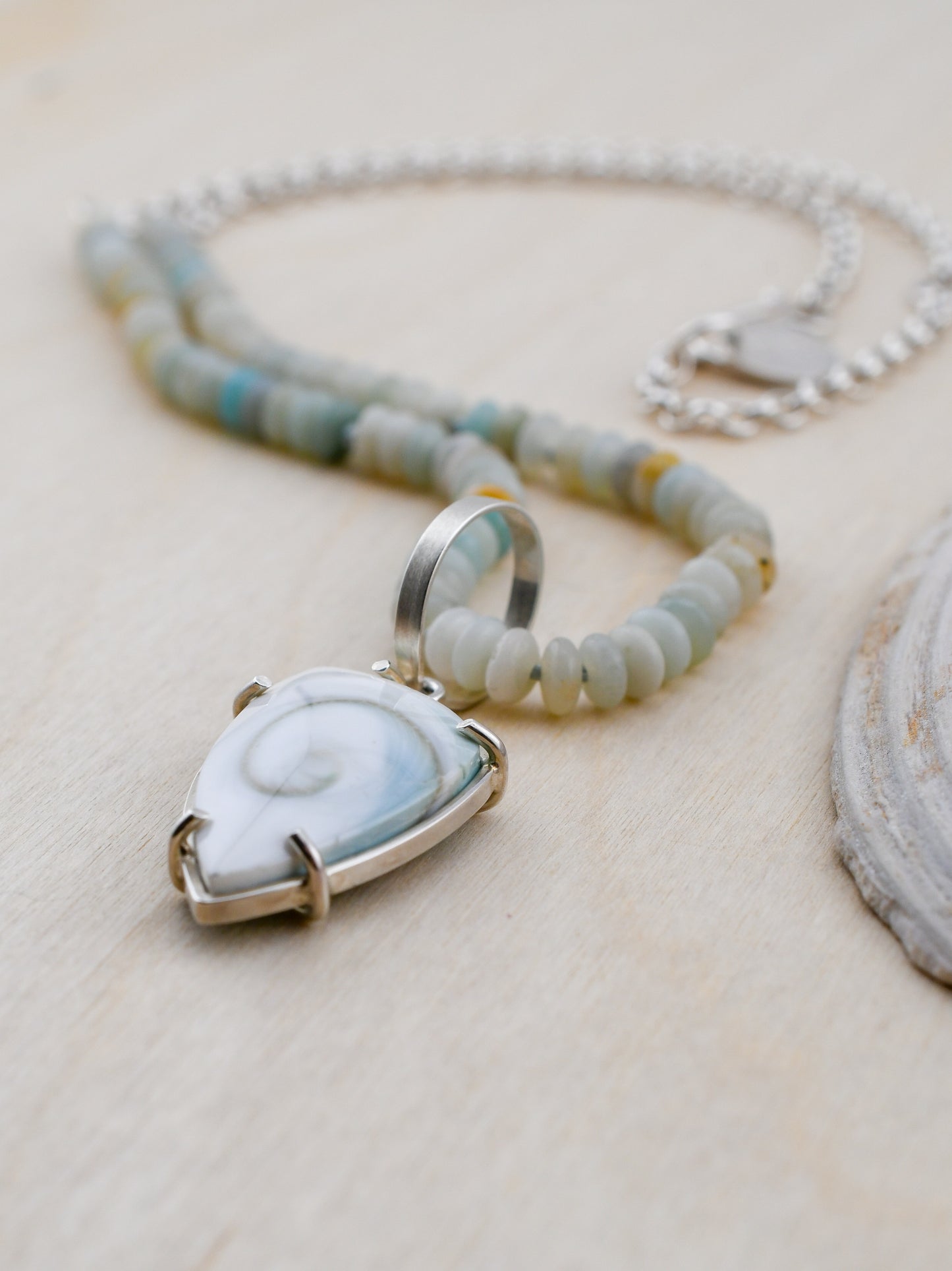 Necklace with a pendant featuring a shell design on a light wooden surface