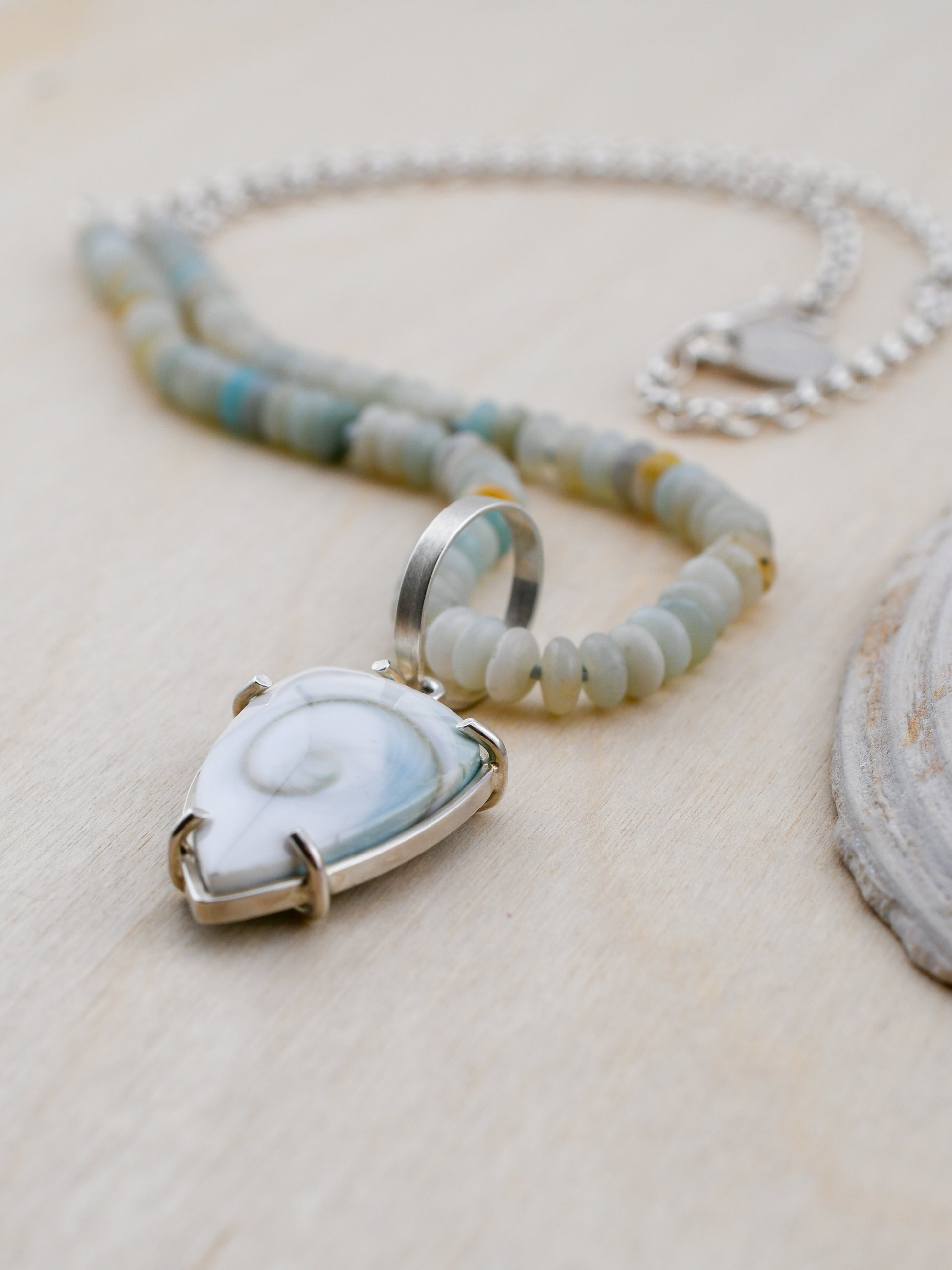 Necklace with a pendant featuring a shell design on a light wooden surface