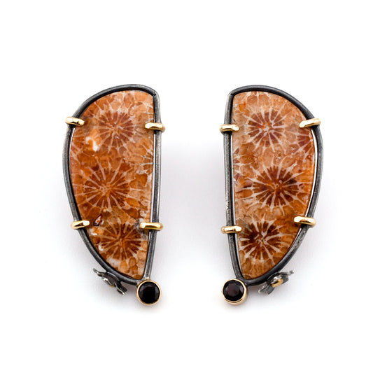 Orange and red free-form fossil coral post earrings set in blackened sterling silver with 14k gold prongs and flower accents and dark red garnets displayed on a white background