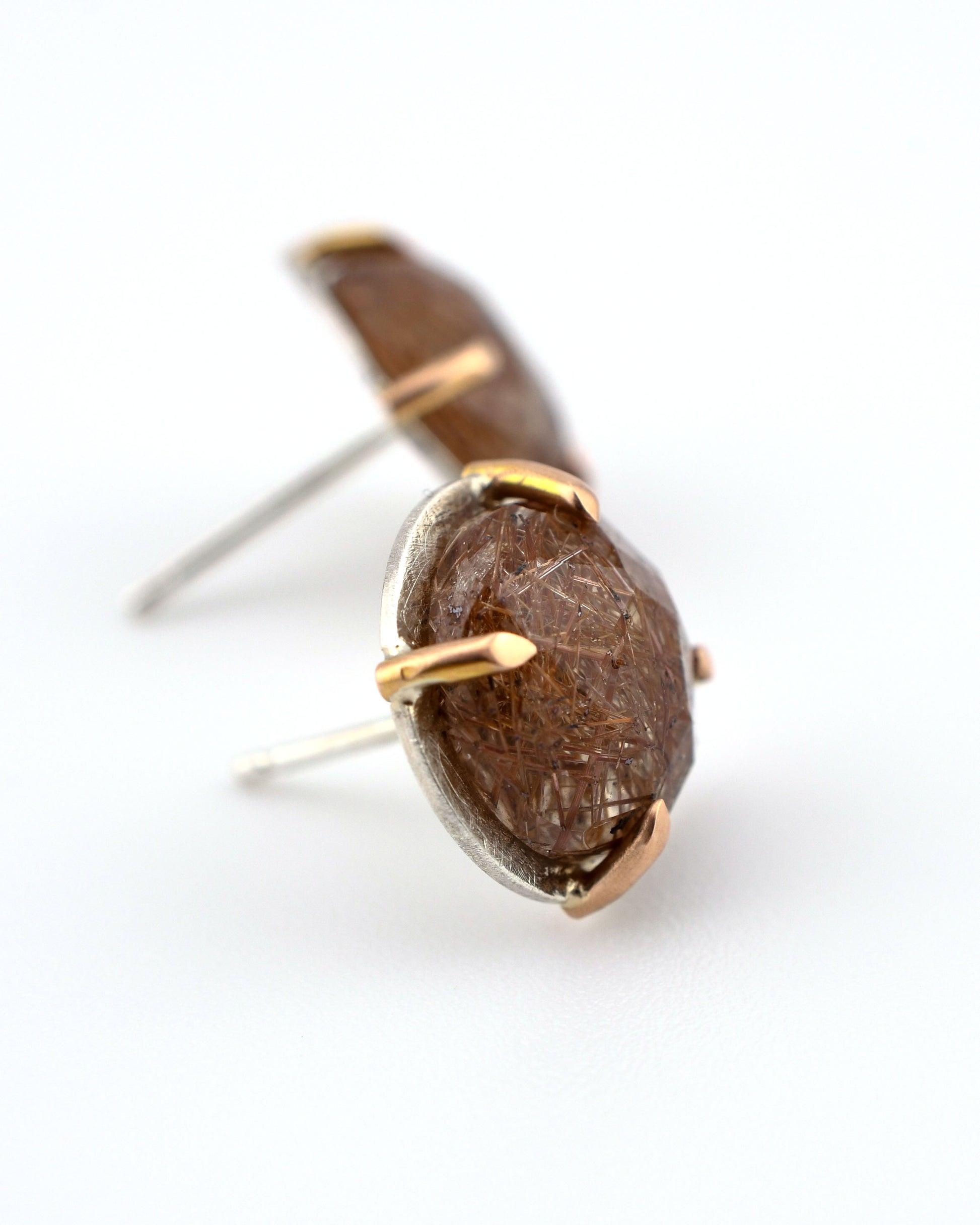 silver and rose gold round stud earrings with red rutilated quartz on a white background