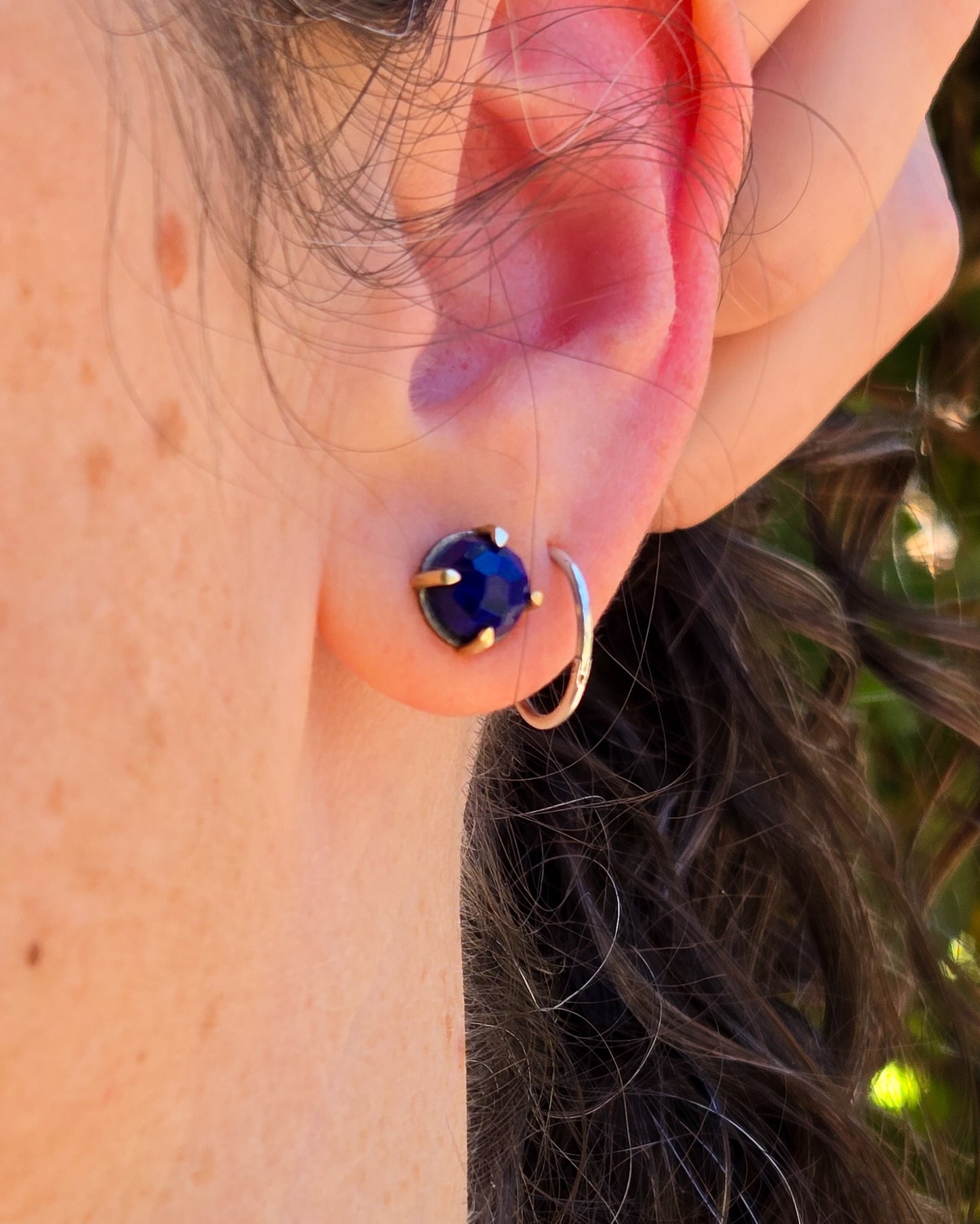 silver and gold lapis studs shown worn on an ear in natural light