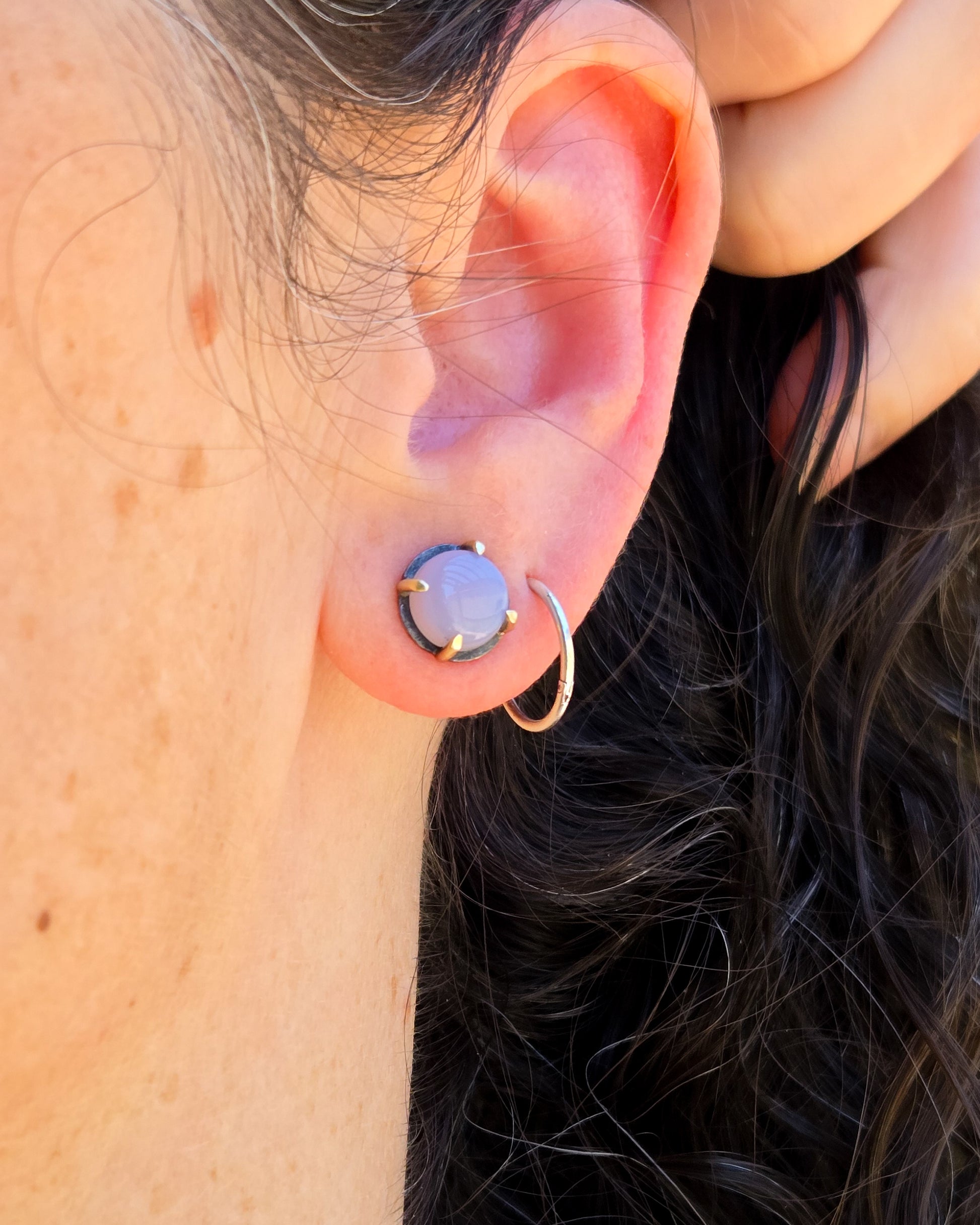 round silver and 14k gold studs with purple chalcedony shown worn on an ear in natural light