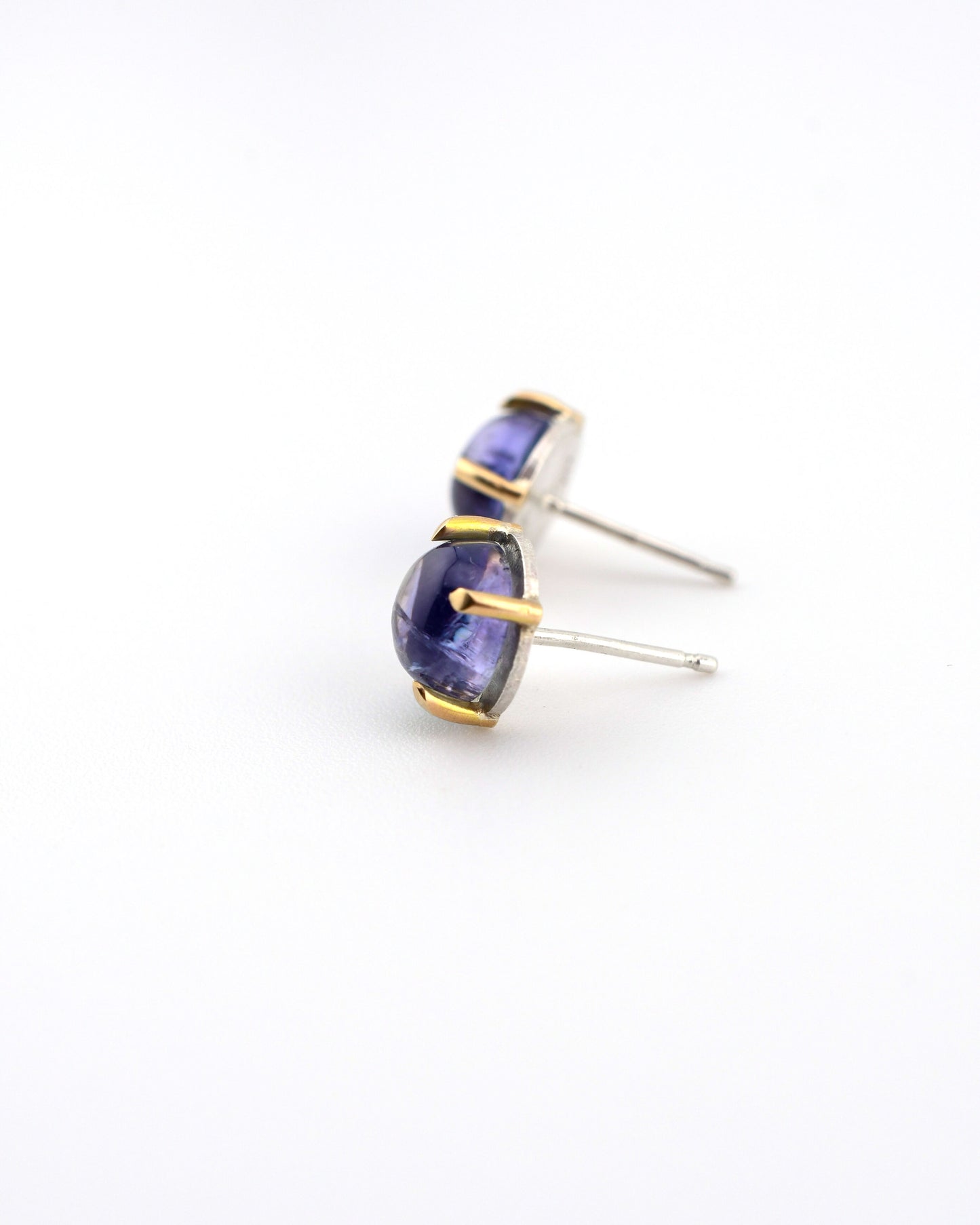 pair of silver and 14k gold stud earrings with tanzanite on a white background