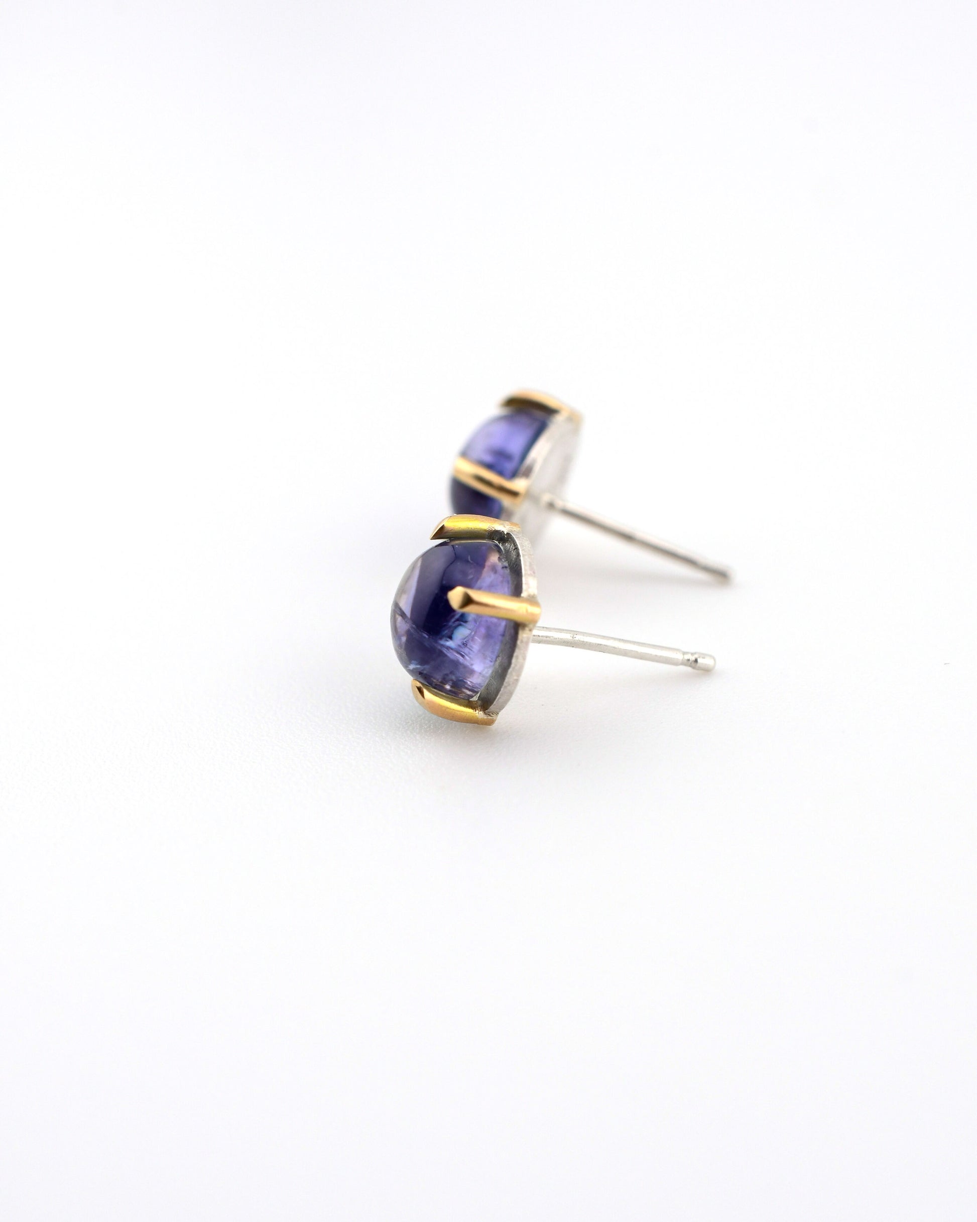 pair of silver and 14k gold stud earrings with tanzanite on a white background