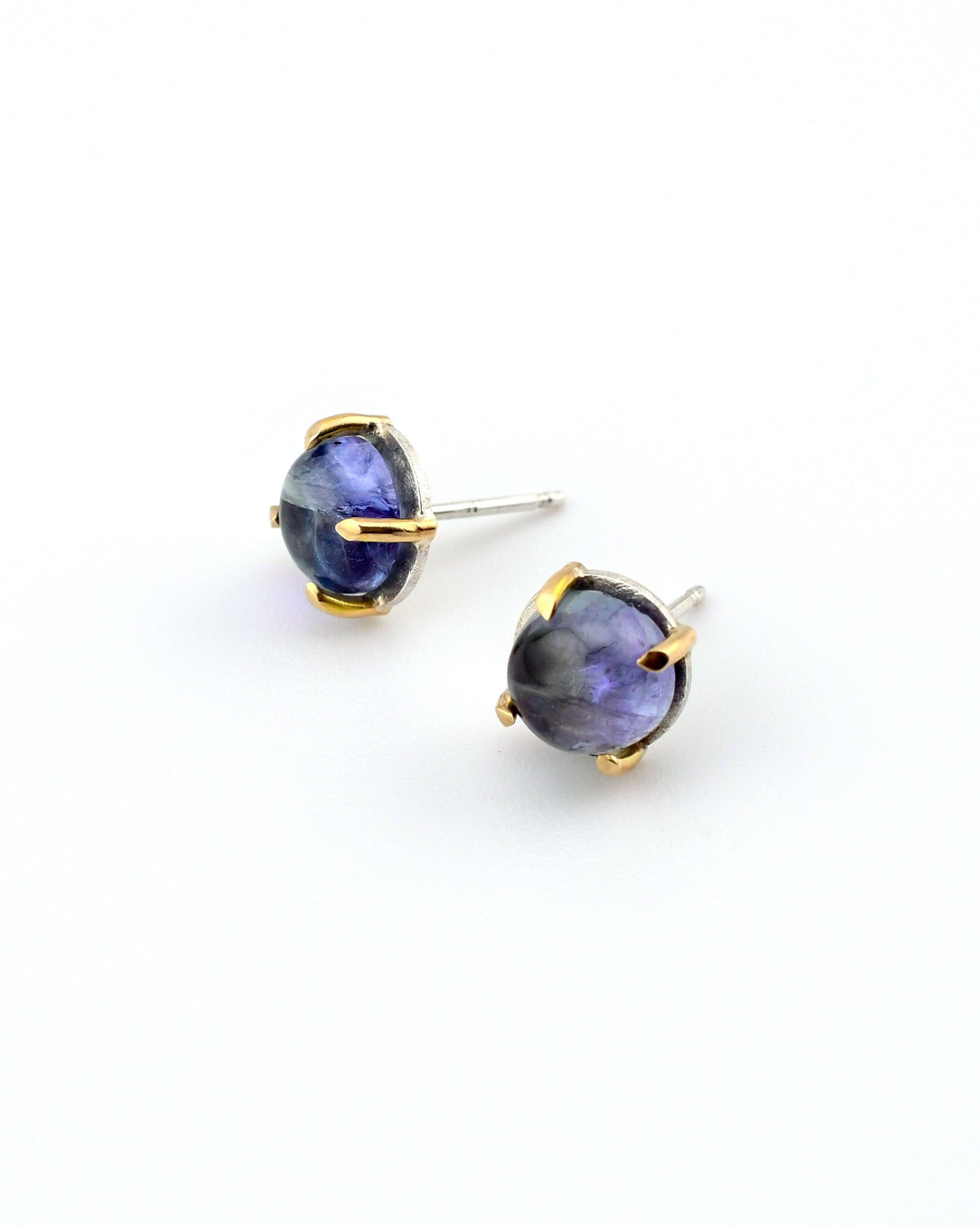 tanzanite stud earrings in silver and 14k gold on a white background
