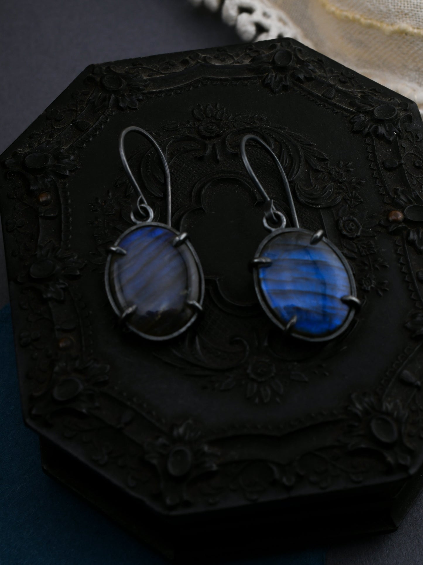 Blue stone earrings on a dark, ornate stand