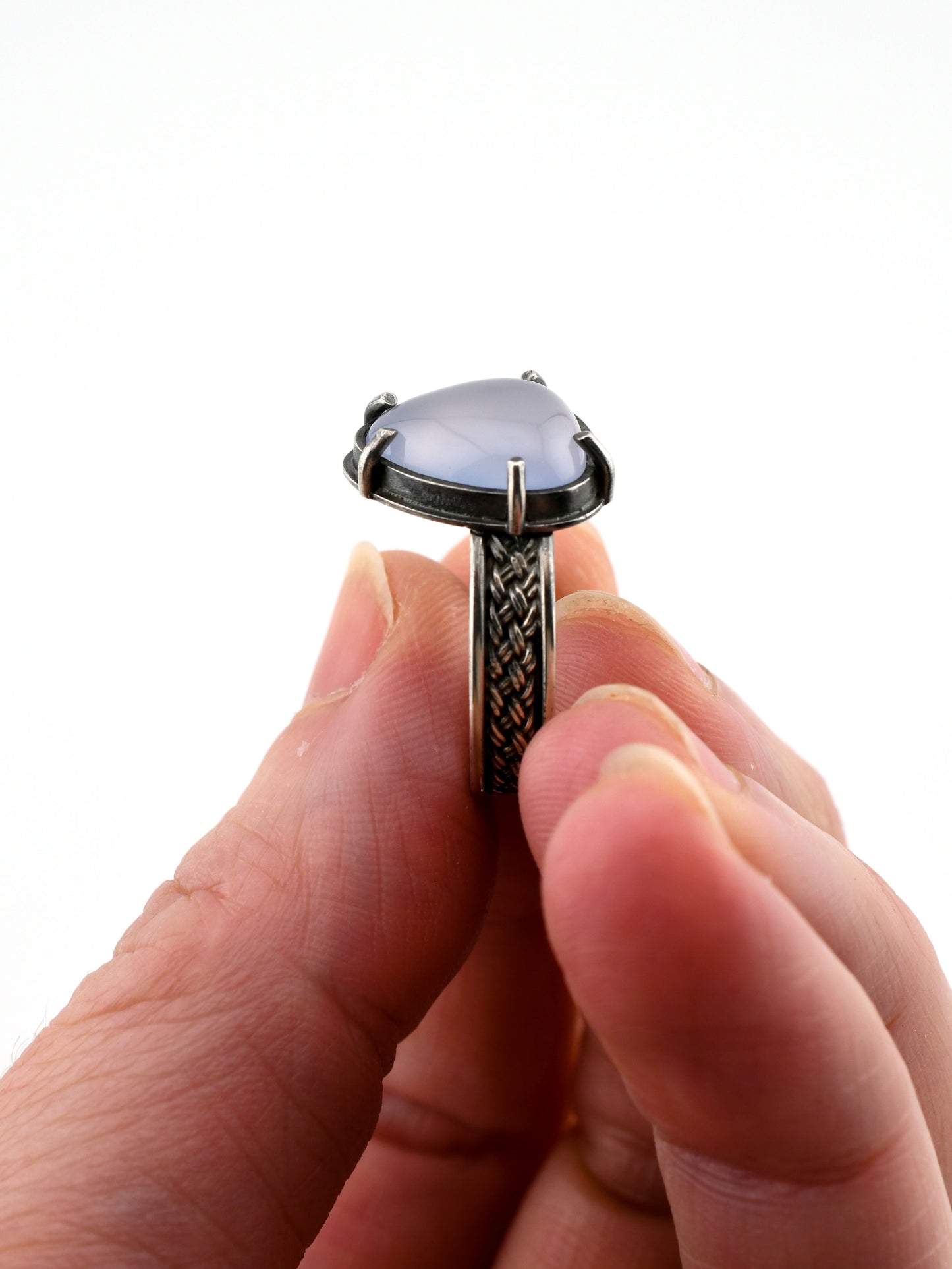 Hand holding a ring with a pale lavender gemstone on a white background