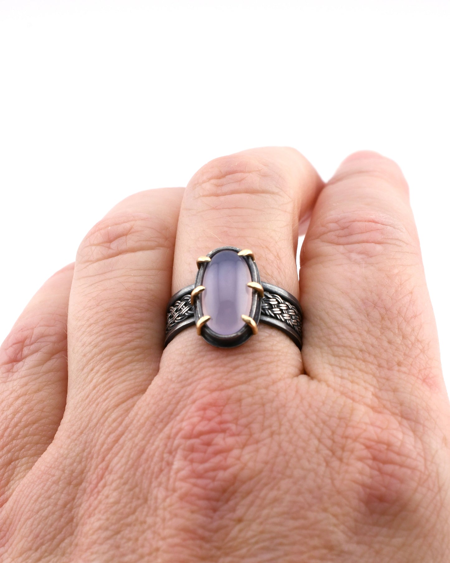 Hand wearing a ring with a purple gemstone on a white background